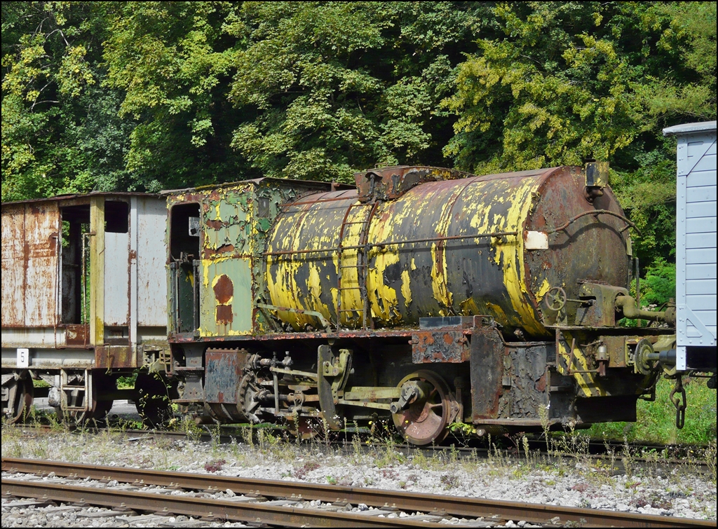 . Verborgene Sch�tze bei der Museumsbahn Train 1900 in Fond de Gras - Am 13.09.2009 fiel mir bei einem Rundgang �ber das Gel�nde der Museumsbahn diese feuerlose Lok auf und wurde bildlich festgehalten. (Hans)

Technische Daten:

Feuerlose Lokomotive No 123, zweiachsig, von ARBED Differdingen (vormals HADIR)
Erbaut im Jahre 1928 von  La Meuse  in L�ttich, Fabriknummer: 3332
Leistung 285 PS, Gewicht 38 t.

Das Funktionsprinzip einer feuerlosen Dampflokomotive sieht folgenderma�en aus: Der �bliche Lokomotivrahmen tr�gt einen zylinderf�rmigen Druckbeh�lter der etwa bis zur H�lfte mit Wasser gef�llt ist. �ber eine mobile Verbindung tritt ein Dampfstrahl von etwa 10 bar, der von einer station�ren Dampfkesselanlage geliefert wird in den wassergef�llten Bereich. Demzufolge wird das Wasser erw�rmt und nach einiger Zeit (etwa einer halben Stunde) hat sich im Druckbeh�lter der Zustand eingestellt, der dem zugef�hrten Dampf entspricht (Druck 10 bar, Wassertemperatur 200� C). Die Lokomotive wird von der F�llstation losgekuppelt und im Dampfraum oberhalb des Wasserspiegels wird Dampf entnommen, der die Lokomotive antreibt. In dem Masse wie Dampf entnommen wird, f�hrt die im Wasser gespeicherte W�rmemenge zu Dampfentwicklung: Die Temperatur des Wassers sinkt und entsprechend der Druck des zur Verf�gung stehenden Dampfes. Ist ein Druck von ca. 2 bar erreicht, f�hrt die Lokomotive die n�chstgelegene F�llstation an, und der Zyklus beginnt von Neuem.
