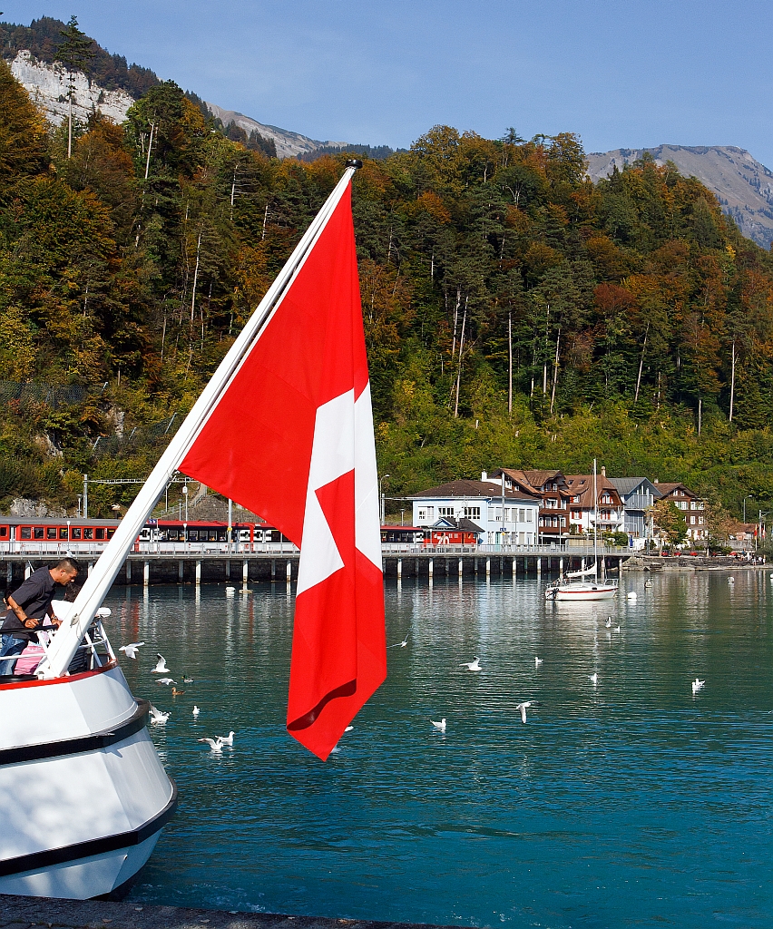 Mein Blick vom Schiffsanleger Brienz, am Heck der MS Brienz vorbei �ber den Brienzersee zum Bahnhof, dort ist eine De 110 der Zentralbahn mit einem IR (Interlaken - Luzern) eingefahren (30.9.2011).