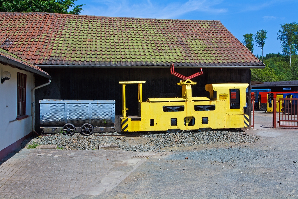 Vor dem Eingang zum Feld- und Grubenbahnmuseum Fortuna, Solms-Oberbiel (FGF) ist (am 07.07.2013) ist die AEG Gruben-Fahrdrahtlokomotive EL 5 (FGF Lok 62) mit einer Lore ausgestellt.

Die Lok war zuletzt im Steinkohlenbergwerk Friedrich-Heinrich bei Kamp-Lintfort im Einsatz. Diente dort zuletzt schon als Ersatzteilspender, daher war an eine betriebsf�hige Aufarbeitung nicht mehr zu denken.

Die Verwendung von Fahrdrahtlokomotiven im Steinkohlenbergbau war wegen der Funkenbildung zwischen Stromabnehmer und Fahrdraht immer problematisch. Um eine absolute Sicherheit vor Gasexplosionen zu gew�hrleisten, durften die Loks nur in Strecken fahren, in denen der Methangasgehalt unter 0,2 % lag (normaler Maximalwert 1 %). F�r einen Einsatz in Abbaun�he kam sie folglich kaum in Frage. Au�erdem kam es immer wieder zu Unf�llen, wenn Bergleute den Fahrdraht versehentlich mit Eisenteilen ber�hrten.

Technische Daten:
Hersteller:  AEG
Baujahr:  1930
Type:  EL 5
Bauart:  Bo-e
Leistung:  2x25 kW
Dienstgewicht:  8,0 t
L�nge �ber Puffer:  4.580 mm
Breite:  900 mm
H�he:  1.680 mm
Achsstand:  1.100 mm
