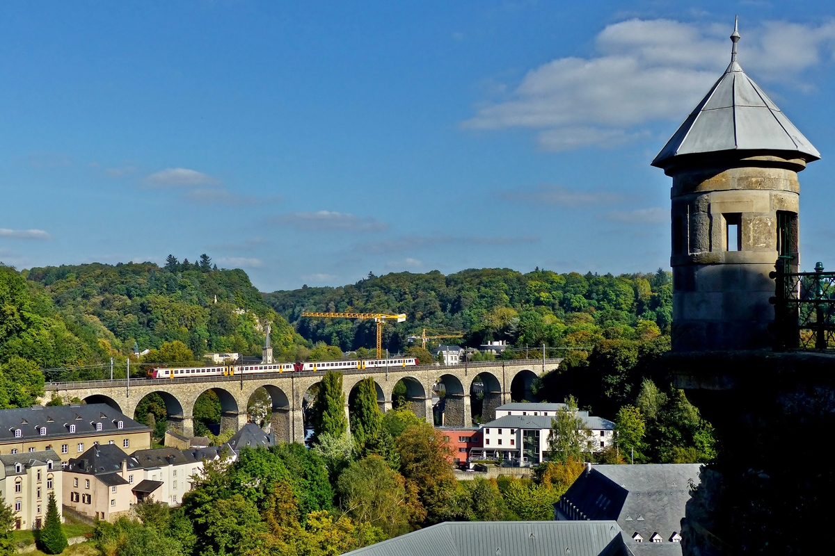 . Herbstbeginn in der Stadt Luxemburg - Der Versuch einen �berrest der Festung Luxemburg mit ins Bild zu nehmen, als die Doppeleinheit Z 2000 als RB 3440 Ettelbr�ck - Luxembourg den Pfaffentaler Viadukt bef�hrt. 23.09.2014 (Jeanny)

Bei dem Festungs�berrest, der leider teilweise schon im Schatten lag, handelt es sich um ein sogenanntes Spanisches T�rmchen. Die Spanischen T�rmchen in Luxemburg entstanden Mitte des 17. Jahrhunderts als Teil der gro�en Befestigung, die von den Spaniern begonnen und unter Vauban fortgesetzt wurde. Der eigentliche Zweck der T�rmchen ist bis heute nicht einwandfrei gekl�rt. Es soll bis zu 38 solcher T�rmchen gegeben haben, davon sind heute noch acht erhalten.