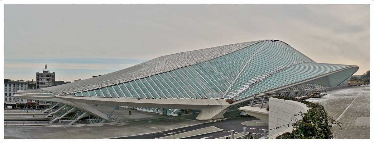 . Wie ein UFO schmiegt sich der Bahnhof Li�ge Guillemins an die  Colline de Cointe  und passt nicht so recht zu dem umliegenden Bauten des  Quartier des Guillemins  in der fr�heren Industriestadt L�ttich. 16.01.2010 (Hans)

Die beiden Stadtteile  Colline de Cointe  und  Quartier des Guillemins  werden heute durch den neuen Bahnhof verbunden, nachdem sie 170 Jahre durch den alten Bahnhof getrennt waren. Der Name  Guillemins  stammt �brigens von einem Kloster aus dem Mittelalter, welches  St Guillaume  gewidmet war und in diesem Stadtteil stand. Die M�nche wurden  Guillemins  genannt und sp�ter wurde dieser Name f�r den ganzen Stadtteil �bernommen. 

Die Aufnahme besteht aus drei Einzelbildern, die als Panorama zusammengef�gt wurden.
