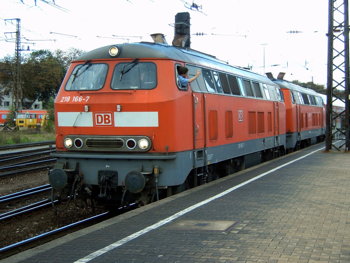 218 166-7 und eine weitere 218 mit einem Autoreisezug kann aus Ulm abfahren. Der Zugführer hat in Handy-Abstimmung mit dem Stellwerk dem Lokführer (der die Signalstellung ja nicht sehen kann) die freie Abfahrt aus der offenen Wagentür des ersten Wagens weitergegeben. Der Lokführer bestätigt per Handzeichen und fährt los. Ulm am 17.09.2005.