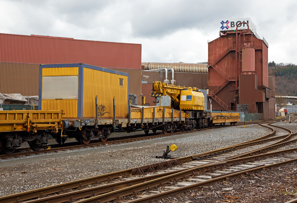 
50t-KIROW-Schienenkran TELVAR 50-1 der Hering Bau (Burbach),  Schweres Nebenfahrzeug Nr. 97 82 35 501 19-1,  mit dem Schutzwagen 80 80 3900 001-9 D-HGUI (Gattung Rs) und einem Res (mit unbek, Nr.), abgestellt am 09.03.2019 in Siegen-Eintracht auf dem Gel�nde der KSW Kreisbahn Siegen-Wittgenstein GmbH. 

Der Eisenbahndrehkran wurde 1992 von der Schwermaschinenbau KIROW Leipzig GmbH  (bis 1990 zum TAKRAF Kombinat) unter der Fabriknummer 1 gebaut. Er war wohl der erste gebaute Kran nach der Reprivatisierung 1990,  bis dahin bestand das TAKRAF Kombinat aus 26 Einzelbetrieben, zu denen auch der VEB Schwermaschinenbau S. M. Kirow Leipzig geh�rte.

TECHNISCHE DATEN:
Spurweite: 1.435 mm
Eigengewicht: 120 t
L�nge �ber Puffer: 13.600 mm
Achsanzahl: 6 (in zwei Drehgestellen)
Drehzapfenabstand: 6.000 mm
Achsabstand in den Einzeldrehgestellen: 3.000 mm (2x 1.500 mm)
Treib- und Laufraddurchmesser: 920 mm (neu)
Fahrgeschwindigkeit im Zugverband: 120 km/h
Fahrgeschwindigkeit mit Eigenantrieb: 20 km/h ohne Last 6 km/h mit Last
Zugelassen als Schwerwagen f�r Streckenklasse: CS04 und h�her
kleinster befahrbarer Radius: 80 m
Bremse: KE-GP

Tragf�higkeiten:
bei  8,00 m Ausladung vor Puffer:  50 t, freistehend: 46 t
bei 18,00 m Ausladung vor Puffer: 17 t, freistehend: 46 t
Hubgeschwindigkeit: bis 30 t 5,3m/min, bis 50 t 3,5 m/min
