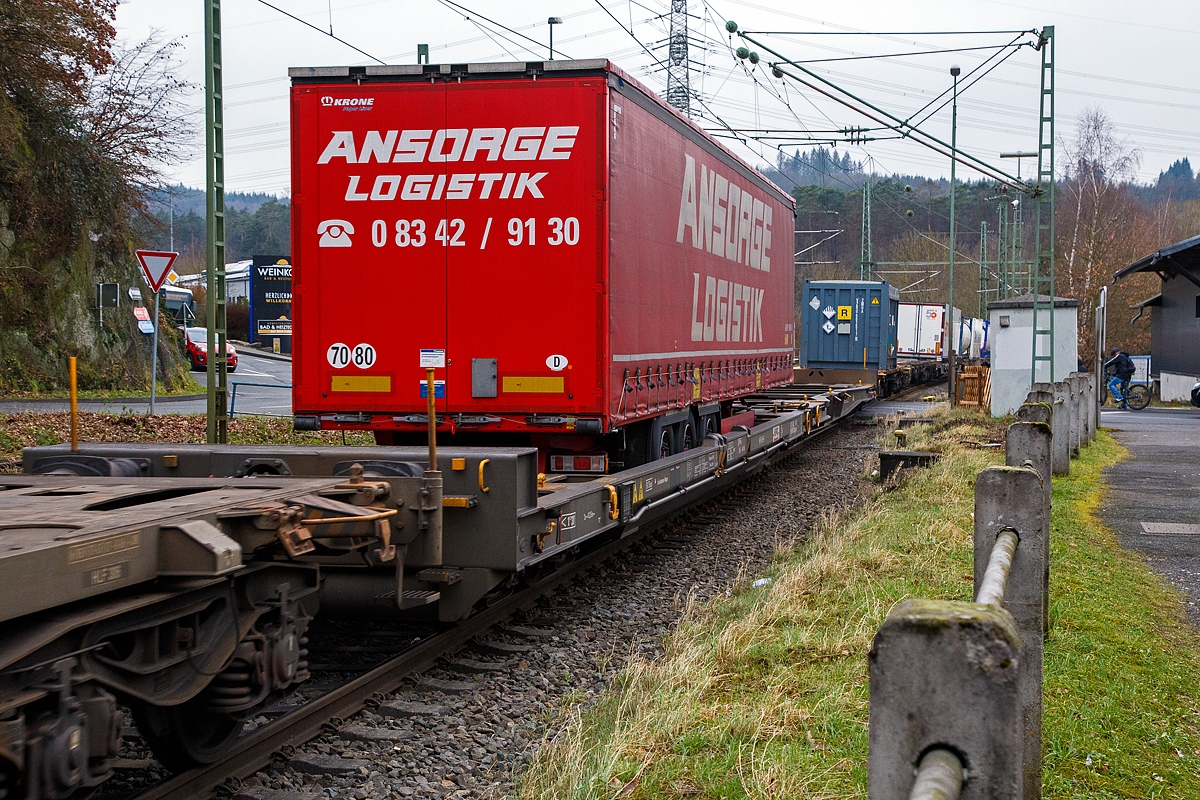 Achtachsiger niedrig gelegte Doppelwagen Jumbo II / Mega II (Trag-/Taschenwagen-Doppeleinheit) der Gattung Sdggmrrss, 83 85 4933 045-5 CH-HUPAC, der Hupac Intermodal SA, am 15.01.2022 im Zugverband bei einer Zugdurchfahrt in Scheuerfeld (Sieg). Diese Wageneinheiten bestehen aus einer niedrigen Taschenwagenh�lfte („SK“) und einer niedrigen Tragwagenh�lfte f�r Container und Wechselbeh�lter („CT“). Die beiden Wagenh�lften sind mit einer, im Normalbetrieb nicht zu trennenden, (von den Waggons der RoLa, Saadkms 690, abgeleiteten) Kurzkupplung verbunden.

Der niedrig gelegte Doppelwagen Mega II ist fast 37 Meter lang. Er wurde 2003 eingef�hrt und ist heute auf allen Shuttle Net-Relationen der HUPAC im Einsatz. Der Mega-Wagen erm�glicht den Transport von Standard- und Megatrailern mit einer verf�gbaren Innenh�he von 2,55 bis 3,0 Metern je nach Streckenprofil. Durch die niedrig gelegte Ladefl�che k�nnen C 70-400 kodifizierte Jumbo-Wechselbeh�lter bis Norditalien und High-Cube-Container bis S�ditalien auf der Gotthardstrecke transportiert werden.

Zus�tzlich der Eignung f�r die neuen Megatrailer, wegen deren Umschlagtechnik mittels tiefliegenden Greifkantenbeschl�gen ein sehr niedrig aufbauender Wagenrahmen erforderlich ist, sollten auch Container und Wechselbeh�lter mit gro�en H�henmassen alpenquerend bef�rdert werden k�nnen. Damit war ein �ber die Ladel�nge nicht in der H�he gekr�pfter Wagenrahmen erforderlich. Die verglichen mit der „Standardh�he“ von 1.175 mm �ber Schienenoberkante (SOK), sehr niedrige Aufstandsh�he von nur 855 mm des MEGA II machte den Einsatz von Drehgestellen der Bauart Y31 Lsi(f) notwendig. Diese weisen eine geringere Bauh�he, durch kleinere Rads�tze mit 760 mm Laufkreisdurchmesser und maximal 18 t Radsatzlast, auf.

Hersteller dieser Wagen ist die Ferriere Cattaneo in Giubiasco (Schweiz), die 115 Wagen (230 Wagenmodule) hergestellt hat. 