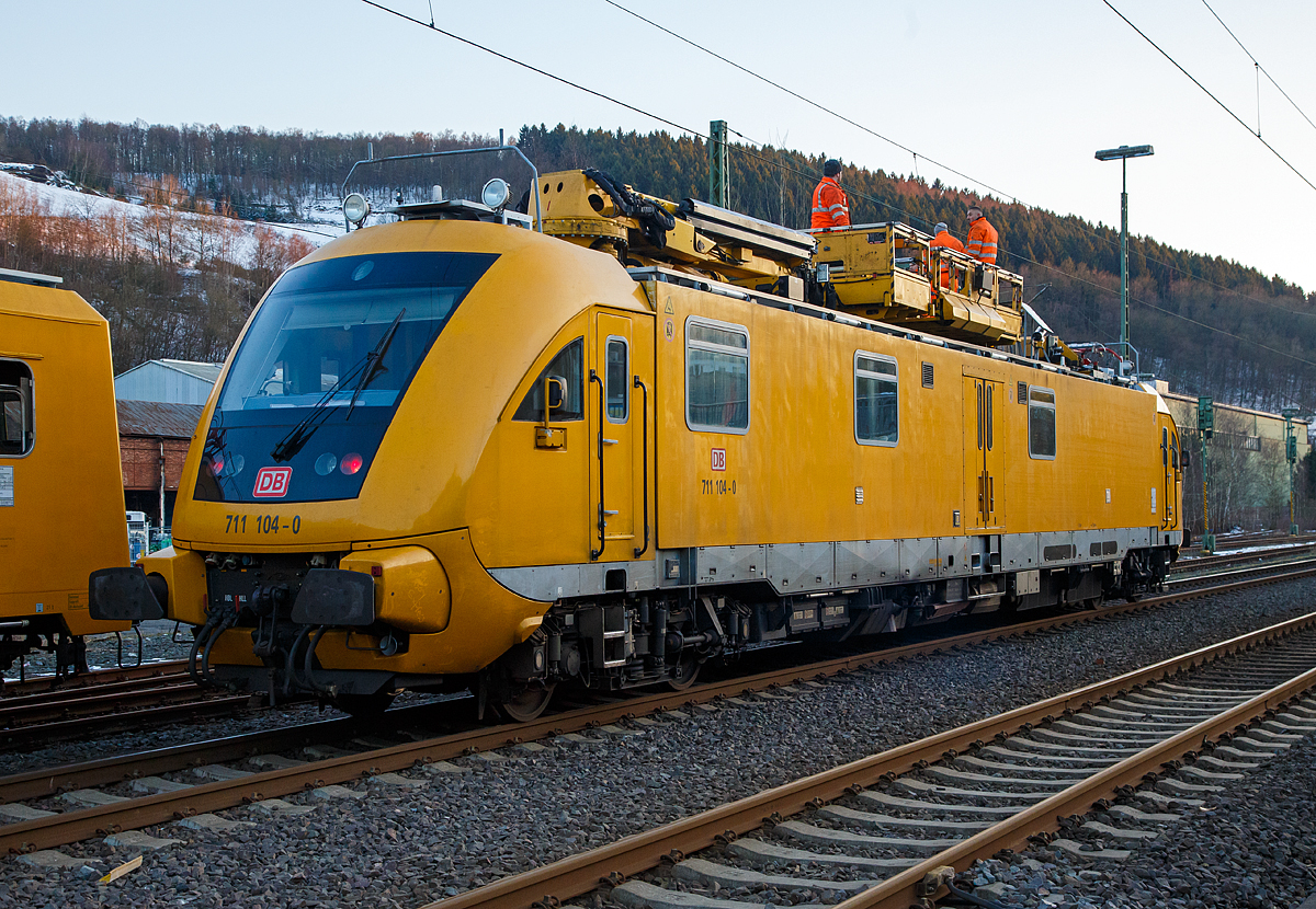 
Am frühen Morgen des 13.02.2018 hatte ein Lkw alle vier Oberleitungen am Bahnübergang Charlottenhütte (an der Siegstrecke) in Niederschelden beschädigt. Die Bahnstrecke zwischen Siegen und Brachbach war den ganzen Tag gesperrt, für diesen Notfall waren zwei Turmtriebwagen bzw. Instandhaltungsfahrzeuge für Oberleitungsanlagen (IFO) der DB Netz AG den ganzen Tag dort für die Reparaturarbeiten im Einsatz.

Hier das Instandhaltungsfahrzeug für Oberleitungsanlagen (IFO) 711 104-0 der der DB Netz AG.

Das IFO 711 104-0 wurde 2002 von der GBM Gleisbaumechanik Brandenburg/H. unter der Fabriknummer  711.104 gebaut. Der ORT 708 325-6 wurde 1990 von der Waggonbau Görlitz unter der Fabriknummer 20300/9 und als 188 325-5 an die DR geliefert.

Das Instandhaltungsfahrzeug für Oberleitungsanlagen (IFO) 711 104-0 ist ein Fahrzeug der Baureihe 711.1, sie werden auch als Hubarbeitsbühnen-Instandhaltungsfahrzeug-Oberleitungsanlagen (HIOB) bezeichnet. Die Fahrzeuge werden auch auf Schnellfahrstrecken eingesetzt. Diese Baureihe ist moderner und schneller als die Baureihe 711.0. Die Fahrzeuge werden bei der Behebung von Schäden und zur planmäßigen Instandhaltungen im Bereich der Oberleitungsanlagen, Brücken und Tunnel eingesetzt. Es wurden zwischen 2002 und 2004 insgesamt 23 Fahrzeuge dieses Typs von der Gleisbaumechanik Brandenburg hergestellt. Das Hubarbeitsbühnen-Instandhaltungsfahrzeug für Oberleitungsanlagen der Baureihe 711.1 ist ein vierachsiges Schienenfahrzeug in Regelbauart. Die Höchstgeschwindigkeit beträgt in Eigenfahrt 160 km/h, zudem ist es auch für Steilstrecken (bis 68 ‰) zugelassen.

Als Streckenfahrantrieb steht eine 2-Motorenanlage mit einer Leistung von insgesamt 1176 kW (2 x 588 kW) zur Verfügung. Die Leistungsübertragung übernehmen hydro-dynamische Getriebe.

Für den Arbeitseinsatz ist ein weiterer kleinerer Dieselmotor mit 130 kW Leistung installiert. Dieser Motor arbeitet ausschließlich im Zusammenhang mit einem Russpartikelfiltersystem.

Mit Hilfe des Arbeitsantriebes werden alle hydraulischen Antriebe versorgt einschließlich des hydrostatischen Fahrantriebes für Arbeitsfahrt. Das Laufwerk des Fahrzeuges besteht aus zwei angetriebenen Drehgestellen (alle Radsätze angetrieben). Die Radsätze sind mit jeweils 2 Scheibenbremsen ausgerüstet. Für optimale Ausnutzung der Reibungsverhältnisse sorgen eine Gleit- und Schleuderschutzanlage sowie eine Sandstreuanlage.

Das Fahrzeug besitzt eine durchgehende indirekt, selbsttätige, mehrlösig, wirkende Druckluftscheibenbremse der Bauart KE, zwei hydrodynamische Bremsen / Retarder, eine direkt wirkende Druckluftbremse als Zusatzbremse, eine direkt wirkende elektro-pneumatische Bremse, eine Magnetschienenbremse, eine Federspeicherbremse als Feststellbremse.

Aufbau und Innenraum
Der Aufbau ist in drei Teile gegliedert. An den beiden Enden befinden sich die Kopfsegmente mit den Führerständen, diese sind Zulieferteile der Fahrzeugtechnik Dessau und entsprechen in der Form dem ehemaligen Innovationszug der DB Regio. Zwischen den Kopfsegmenten ist der Wagenkasten mit einer Werkstatt, einem Lagerraum, einer Nasszelle und einem Sozialraum mit einem Arbeitsplatz. Die Werkstatt beinhaltet alle gebräuchlichen Ersatzteile und Werkzeuge zur Instandhaltung und Reparatur an Oberleitungsanlagen, im Werkstattbereich befindet sich dann auch die Nasszelle mit Waschmöglichkeit und Toilette. Die Toilette ist ausgerüstet mit einem Bioreaktor, welcher das Abwasser reinigt und nur noch heißes Wasser an die Umwelt gelangen lässt – der Feststoffbehälter muss nur zur planmäßigen Instandhaltung in einem Ausbesserungswerk entleert werden.

Es folgt der Videoarbeitsplatz mit Monitor zur Beobachtung der Fahrdrahtlage per Kameras, einem Faxgerät und einem Bedienfeld zum Schwenken der Kamera und des Dachscheinwerfers. Gegenüber dem Videoarbeitsplatz befindet sich eine kleine Küchenzeile mit Mikrowelle, Wasserkocher, Kaffeemaschine, Schränken, Trinkwasserbehälter und einem Abwaschbecken.

Vorbei an der Hydraulik für die freischwenkbare Hubarbeitsbühne gelangt man in den Aufenthaltsraum mit Radio, Sitzgelegenheiten, einem Tisch und Trockenschränken für Kleidungsstücke, hieran schließt durch eine Tür abgetrennt der zweite Führerstand an.

Dachausrüstung
Auf dem Dach sind zwei Hubarbeitsbühnen vorhanden, eine als freischwenkbare (Palfinger PA 360) und eine als nur in der horizontalen Richtung zu bewegende (Palfinger PA 90), beide können gekuppelt und somit die Nutzfläche vergrößert werden. Es wurden auf dem Dach außerdem ein Seildrücker und ein Stromabnehmer mit einstellbarer Anpresskraft, Videoüberwachung sowie diverse Beleuchtungskörper installiert. Die freischwenkbare Hubarbeitsbühne PA 360 hat einen Arbeitskorb mit 1.500 mm × 1.600 mm Abmessung und kann 18,5 m über SO und etwa 10 m unter SO erreichen. Die Hubarbeitsbühne PA 90 besitzt die Abmessungen 3.500 mm × 1.600 mm, erreicht 6 m über SO und kann zu beiden Seiten um 90 Grad gedreht werden.

Beide Bühnen können über eine Gegengleissperre gesichert werden, um nicht aus Versehen in den lichten Raum des Gegengleises zu drehen.

Zur Instandhaltungsausrüstung des Fahrzeuges gehören:
1 Freischwenkbare Hubarbeitsbühne, 
1 Hubarbeitsbühne mit schwenkbarem Arbeitskorb,
1 Fahrdraht- und Tragseildrücker,
1 Stromabnehmer mit Messlineal und einstellbarer Anpresskraft,
1 Messsystem für ein- und auslaufende Kettenwerke,
1 Videoanlage zur Beobachtung des Stromabnehmers.
Alle Funktionen des Fahrzeuges werden mittels einer Fahrzeugsteuerung gesteuert und überwacht.

Elektrische Ausrüstung
Die Fahrzeuge besitzen eine komplexe elektrische Ausrüstung, die über eine Speicherprogrammierbare Steuerung (SPS) so gut wie alle Fahrzeugfunktionen überwacht und ausführt. Auf diese Art wird eine Fehlbedienung weitestgehend ausgeschlossen, sicherheitsrelevante Einstellungen werden zuverlässig eingehalten. So ist es zum Beispiel durch die SPS nicht möglich, mit eingelegter Federblockierung schneller als 15 km/h zu fahren. Wenn sich ein Dachgerät wie Arbeitsbühne oder Seildrücker nicht in Transportstellung befindet, ist es nicht möglich in die Streckenfahrt überzugehen. Außerdem kann ein „Einmotorbetrieb“ genutzt werden, bei dem die Wahl zwischen dem Fahrmotor 1 oder 2 besteht oder der Motor mit den wenigsten Betriebsstunden genutzt wird. Auch die Außenbeleuchtung (Dreilicht-Spitzensignal und Arbeitsfeldbeleuchtung) werden per SP-Steuerung gesteuert.

Obligatorisch ist die Ausrüstung mit einer Indusi der Bauart Siemens I 60R in der Softwareversion PZB 90 V2.01. Es gibt zwei Zeit/Zeit-Sicherheitsfahrschaltungen, eine software-basierende für die Arbeitsfahrt und eine hardware-basierende für die Streckenfahrt. Weiterhin dient ein GSM-R Zugfunkgerät der Verständigung mit angeschlossenen Stellen. 

TECHNISCHE DATEN:
Spurweite: 1.435 mm (Normalspur)
Achsformel:  B'B'
Länge über Puffer: 24.640 mm
Drehzapfenabstand: 17.000 mm
Achsabstand in den Drehgestellen: 2.600 mm
Breite: 2.875 mm
Höhe: 4.650 mm
Raddurchmesser: 920 mm (neu) / 860 mm (abgenutzt)
kleinster befahrbarer Gleisbogen: R= 150 m
Leergewicht: 78,7 t
Nutzlast: 	 5,2 t
Dienstgewicht: 84 t
Zur Mitfahrt zugel. Personenzahl: 9
Höchstgeschwindigkeit: 160 km/h / geschleppt 120km/h / Arbeitsfahrt 10 km/h
Anfahrzugkraft: 64 kN

Antrieb 	 
Fahrmotor: zwei Dieselmotoren vom Typ MAN D2842 LE602, EURO 2 mit je 588 kW Leistung
Max. Drehzahl: 2.100 U/min
Max. Drehmoment: 	3.200 Nm bei 1.300-1.600 U/min

Arbeitsmotor: ein Dieselmotor vom Typ MAN D0826 LOH 19, EURO 2 mit 130 kW Leistung
Max. Drehzahl: 1.500 U/min
Max. Drehmoment 	825 Nm bei 1.700 U/min

Getriebe: 	Voith-Turbogetriebe T311 bre;
