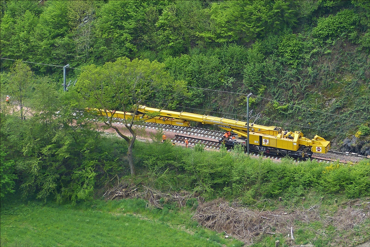 Der 150 t Kirow Gleis- und Weichenbaukran KRC 1200 (ein Kirow MULTI TASKER KRC 1200)  99 81 9119 004-5 der Firma Swietelsky bei Gleisbauarbeiten im Bahnhof Kautenbach. Auf dem Foto hat der Kran den Tunnel mit seiner Last durchfahren und wird in k�rze das Gleisst�ck an das Ende des bisher verlegtem Gleis ablegen.  16.05.2016 (Hans)