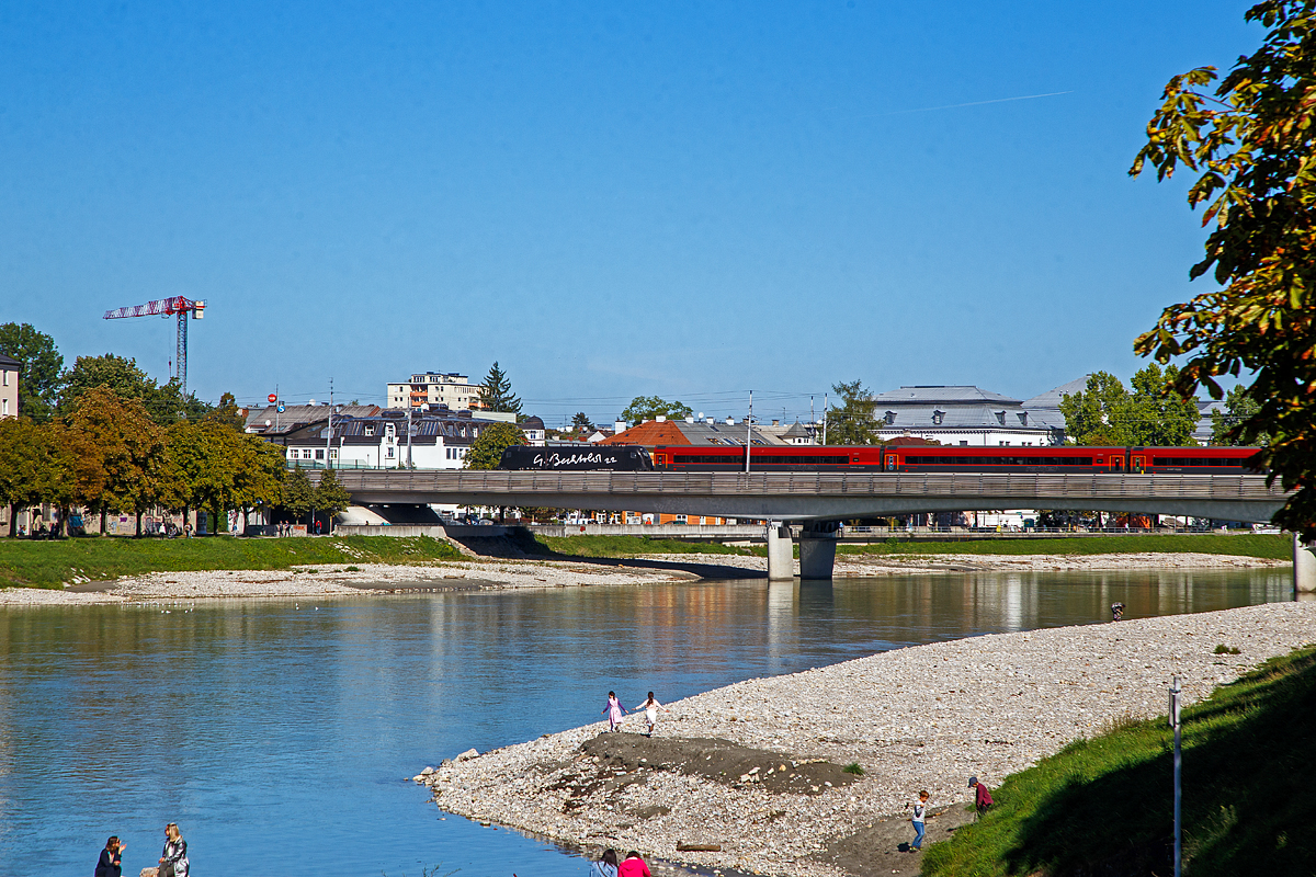 Der Taurus II ÖBB 1116 229–6 (A-ÖBB 91 81 1116 229-6), überquert einen ÖBB Railjet schiebend, am 12.09.2022 die Salzach und erreicht bald den Hauptbahnhof Salzburg.

Die Lok ist komplett schwarz beklebt bis auf weißen Schriftzug  G. Bechtold 22  auf der Seite, es ist ein Kunstprojekt des österreichischen Künstlers Gottfried Bechtold. Was daran Kunst entzieht sich meiner Kenntnis, oder ich bin ein Kunstbanause. 

Die Elektrische Universallokomotive vom Typ Siemens ES64U2  (Taurus II)  wurde 2004 von Siemens im TS Werk Linz unter der Fabriknummer 20950 gebaut und an die ÖBB (Österreichische Bundesbahnen) als 1116 229-4 geliefert. Sie hat die Zulassungen für Österreich, Deutschland und Ungarn.