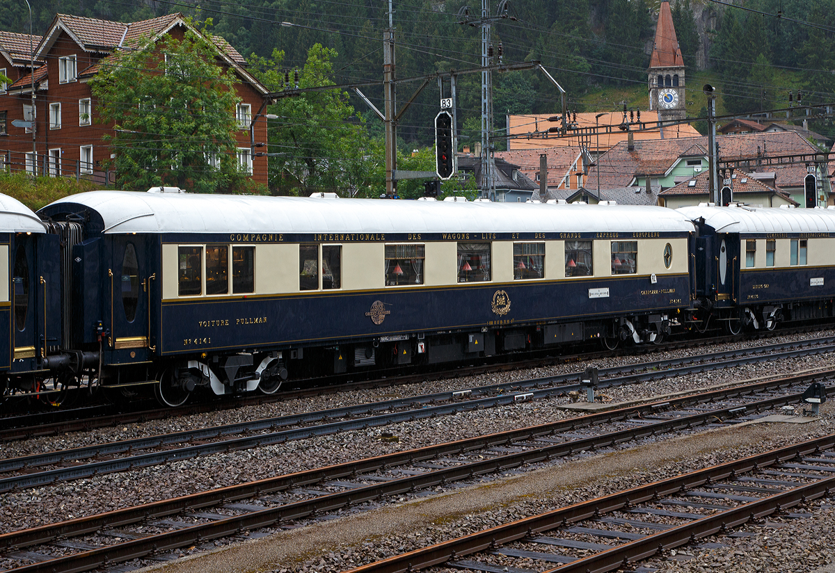 Der VSOE Pullman Speisewagen N� 4141 (F- VSOE 61 87 09-70 141-0 [P]), ex CIWL 4141, im Zugverbund vom Venice Simplon-Orient-Express am 02.08.2019 beim Halt in G�schenen (CH), leider bei Regen.

Der Pullman-Speisewagen N� 4141 wurde 1929 als erstklassiger Pullman - Wagen (Voiture - Pullman / Carrozza – Pullman) vom Typ  C�te d'Azur  von EIC- Entreprises industrielles des Charentes (EIC, heute zu Alstom geh�rend) in Aytr� (F) gebaut und an die CIWL (Compagnie Internationale des Wagons-Lits) geliefert die ihn als Nr. 4141 bezeichnete. Das Innendesign wurde vom bekannten franz�sischen Schmuck- und Glask�nstler des Art D�co von Ren� Lalique im  C�te d'Azur  -Stil gestaltet und dekoriert. In die Mahagoniseiten des Wagens montierte er Glasscheiben mit Darstellungen vom  Bacchanalian-M�dchen .  Das blaue undurchsichtige Glas zeigt verschiedene klassische Figuren, in denen Trauben mit einem passenden Fries aus kleineren Paneelen aufbewahrt werden. Lalique war auch f�r das Design einiger Pullman-St�hle und f�r die  Tulip  -Lichtblenden im gesamten Zug verantwortlich. Der Wagen hatte urspr�nglich nur Zweiertische mit Pl�schsessel mit hohen R�ckenlehnen, die bieten damals wie heute ein Maximum an Komfort. An den Enden des Waggons befanden sich zwei in sich geschlossene S�par�es, mit jeweils vier Pl�tze (Viererabtei), die ein weitgehend ungest�rtes Dinieren in gediegener Atmosph�re erm�glichten.

Der Wagen wurde sofort im C�te d’Azur Pullman Express eingesetzt und wechselte 1933 dann zum Sud-Express. Er fuhr bis 1935 im Sud Express und blieb dann beim L’Oiseau Bleu (Der blaue Vogel) von Amsterdam �ber Br�ssel nach Paris. Nach dem Krieg wurde er zum Etoile du Nord bef�rdert. Im Mai 1947 wechselte er in den Fl�che d’Or und bef�rderte die Passagiere des Golden Arrow (London-Dover) von Calais weiter nach Paris.

Der Wagen wurde 1971 bei der CIWL-Werkstatt in Villeneuve-Saint-Georges (bei Paris) abgestellt. 1981 wurde er von der VSOE Ltd von dem trostlosen Abstellgleis gerettet. Die VSOE lie� den durch die Bremer Waggonbau GmbH (ehem. Hansa Waggonbau) 1982 restaurieren und umbauen. Nach einem Brand im Jahr 1983 wurde die K�che durch einen Souvenirladen ersetzt, die aber 2015 einer Champagner-Bar wich. 

Technik
Mit der Einf�hrung der Ganzstahlwagen ging die CIWL dazu �ber, von Ausnahmen abgesehen alle Fahrzeuge auf einem einheitlichen Rahmen mit 23.452 mm L�nge �ber Puffer und einem Drehzapfenabstand von 16.000 mm aufzubauen. Die Fahrzeugbreite betr�gt 2.850 mm, die H�he �ber Schienenoberkante 4.000 mm. Als Drehgestelle erhielten die Wagen urspr�nglich Schwanenhals-Drehgestelle mit Rollenlagern, auch als Pennsylvania-Drehgestelle bezeichnet. Urspr�nglich waren die Wagen lediglich f�r 130 km/h zugelassen, sp�ter nach auf 140 km/h angehoben. 

1977 begann die von James B. Sherwood geleitete Sea Containers Ltd. historische Wagen der CIWL und der British Pullman Company zu erwerben und aufw�ndig zu restaurieren. Die Wagen wurden daf�r �berholt und technisch modernisiert, unter anderem mit Klimaanlagen. 

Zwischen 2003 und 2006 wurden die Wagen nochmals modernisiert und erhielten unter anderem moderne Drehgestelle von Bombardier sowie neue Klimaanlagen. Seitdem sind die Wagen nun f�r 160 km/h zugelassen.

TECHNISCHE DATEN:
Spurweite: 1.435 mm (Normalspur)
Anzahl der Achsen: 4 in zwei Drehgestellen
L�nge �ber Puffer: 23.452 mm
Drehzapfenabstand: 16.000 mm
Achsabstand im Drehgestell: 2.500 mm
Eigengewicht: 55 t
H�chstgeschwindigkeit: 160 km/h (urspr�nglich 140 km/h)
Sitzpl�tze: 34