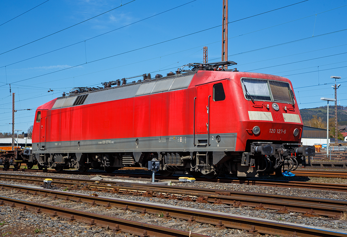 Die 120 127-6 (91 80 6120 127-6 D-BLC) der Bahnlogistik24 GmbH (Dresden) ist am 17.04.2022 in Kreuztal angestellt. Eigentümer der Lok ist die Nürnberger Leasing GmbH (Schwaig).

Die Lok wurde 1987 von Krauss-Maffei in München-Allach unter der Fabriknummer 19958 (die elektrische Ausrüstung ist von Siemens) gebaut DB geliefert. Bis 2021 war sie im Bestand der DB Fernverkehr AG, nun fährt sie für die Bahnlogistik24 GmbH (BLC), wobei Eigentümer der Lok ist die Nürnberger Leasing GmbH (Schwaig).

Eigentlich beträgt die Höchstgeschwindigkeit dieser Baureihe 200 km/h (als BR 120.2 160 km/h), bei dieser konnte ich sehen das sie nur für 140 km/h noch zugelassen ist.

Die Baureihe 120 ist eine Elektro-Lokomotivbaureihe der Deutschen Bahn AG. Sie gilt als die weltweit erste in Serie gebaute Drehstrom-Lokomotive im Hochleistungsbereich mit Umrichter in Halbleitertechnik und ist ein Meilenstein in der Entwicklung elektrischer Lokomotiven. Sie repräsentierte zu ihrer Zeit den letzten Stand der Entwicklung des Drehstromantriebs, bei dem aus dem Wechselstrom der Fahrleitung in Traktionsstromrichtern der Drehstrom zum Antrieb der Asynchron-Fahrmotoren gewonnen wird. Ausgehend von der Technologie der Baureihe 120 wurden Mitte der 1980er Jahre die ersten ICE-Triebköpfe entwickelt. Bis 2020 wurden fast alle sich noch im Einsatz befindlichen Loks der Baureihe 120 abgestellt, wie dies bereits 2019.

Die Serienlok BR 120.1:
Nach vierjähriger Erprobung wurden 1984 insgesamt 60 Serienlokomotiven der Baureihe 120.1 zu einem Stückpreis von 5,5 Millionen D-Mark bestellt.

Die technischen Änderungen im Vergleich zu den Prototypen waren gering, so entfiel beispielsweise die als Rückfallebene eingebaute elektrische Widerstandsbremse, da sich die Nutzbremse entgegen ersten Erwartungen als zuverlässig herausgestellt hatte. Dafür erhielten die Lokomotiven einen zusätzlichen Hochspannungsfilter, der zwei zusätzliche Dachleitungen erforderlich machte. Diese wurden bei den Vorserienlokomotiven nachgerüstet. Kritisch betrachtet, wurden die mechanischen Schwächen der Vorserienmodelle der Baureihe 120.0 ebenfalls in der Serie beibehalten. Nach erfolgreichen Versuchen mit den für maximal 160 km/h zugelassenen Prototypen 120 001 bis 004 und der bereits für 200 km/h zugelassenen 120 005 konnten die Serienloks für bis zu 200 km/h zugelassen werden.

Am 13. Januar 1987 übergab die Industrie im Bundesbahn-Ausbesserungswerk München-Freimann mit der 120 103 die erste Serien-Drehstromlokomotive an die damalige Deutsche Bundesbahn. Die Auslieferung der Serienloks dauerte bis Ende des Jahres 1989. Sie wurden sofort im planmäßigen Dienst eingesetzt, wobei sie in einem gestrafften Umlaufplan tagsüber Intercity- und Interregio-Züge und nachts schnelle Güterzüge bespannten.

Ausmusterung:
Durch den technischen Fortschritt im Bereich der Schienenfahrzeugtechnik gilt die Baureihe 120 mittlerweile als überholt und zeigt sich zunehmend störanfällig. Der Betriebsbestand der Serienmaschinen bei der DB ist stetig rückläufig. Erste Serienlokomotiven sind bereits verschrottet. Andere Lokomotiven wurden verkauft, wie auch diese hier.

TECHNISCHE DATEN:
Spurweite: 1.435 mm,
Achsformel: Bo`Bo`
Länge über Puffer: 19.200 mm
Drehzapfenabstand: 10.200 mm
Achsabstand im Drehgestell: 2.800 mm
Treibraddurchmesser: 1.250 mm (neu)
Dienstgewicht: 83,2 t
Anzahl der Fahrmotoren: 4
Dauerleistung: 5.600 kW (4 x 1.400 kW)
Anfahrzugkraft: 340 kN (20 137 bis 120 160 nur 290 kN)
Höchstgeschwindigkeit: 200 km/h (als BR 120.2 160 km/h)
Fahrmotoren: 4 Drehstrom-Asynchron-Motoren
Antrieb: Hohlwellen-Kardan-Einzelachsantrieb 
