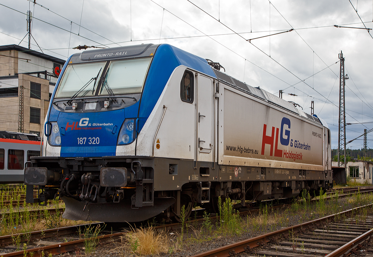 Die 187 320 (91 80 6187 320-7 D-Bebra) der HLG - Holzlogistik und G�terbahn GmbH (Bebra) ist am 31.07.2021 beim Hbf Siegen abgestellt. 

Die Lok Bombardier TRAXX F140 AC3 LM (zugelassen f�r 140 km/h daher Variante F140 und nicht F 160). Sie wurde 2018 von Bombardier in Kassel unter der Fabriknummer 35448 gebaut und an die HLG - Holzlogistik und G�terbahn GmbH in Bebra geliefert. Nach meiner Sichtung hat die Lok die Zulassung f�r Deutschland (D) und �sterreich (A). F�r Ungarn und Rum�nien sind die Zulassungen noch nicht erteilt (H und RO sind durchgestrichen).

Wie die Vorg�ngerinnen AC1 und AC2 ist die AC3 f�r den Betrieb unter 15 Kilovolt bei 16,7 Hertz, sowie unter 25 Kilovolt bei 50 Hertz Wechselstrom ausgelegt, und verf�gt unver�ndert �ber eine Dauerleistung von 5.600 kW und eine Anfahrzugkraft von 300 kN. Von den Traxx 2E �bernommen wurde der Maschinenraum mit Seitengang um das sogenannte Powerpack, bestehend aus Stromrichter und Hochspannungsger�st, womit erstmals alle Varianten dasselbe Layout verwenden.

Neu ist die Kopfform der Traxx-3-Lokomotiven, im Wesentlichen ein auf dem Lokkasten aufgesetztes GFK-Modul. Zudem wurden die Lokomotiven erstmals ab Werk konstruktiv f�r den Einbau der Zugbeeinflussung ETCS vorbereitet. Neuerungen betreffen die verf�gbaren Drehgestelle: zu den bisherigen Varianten „F140“ mit Tatzlagerantrieb und Zulassung f�r maximal 140 km/h, und „P160“ mit Hohlwellenantrieb und Zulassung f�r maximal 160 km/h, werden die Traxx-3-Lokomotiven offiziell auch als Variante „F160“ mit Tatzlagerantrieb und Zulassung f�r maximal 160 km/h angeboten. Es gibt sie also als TRAXX F140 AC3 und als TRAXX F160 AC3.

G�nzlich neu sind die optional verf�gbaren Last-Mile-Module, die es als Last-Mile-Diesel (LMD) mit zus�tzlicher Last-Mile-Battery (LMB) gibt. Das LMD besteht aus einem Dieselhilfsmotor und einem Kraftstofftank, um auch nicht-elektrifizierte Streckenabschnitte und Anschlussgleise befahren zu k�nnen. Der Dieselmotor von Deutz verf�gt �ber einen Hubraum von 7.150 cm�, erbringt eine Leistung von 230 kW (180 kW am Rad), mit Batterieunterst�tzung 290 kW und erf�llt die Stage-IIIB-Abgasnorm. Im Dieselbetrieb werden alle vier Fahrmotoren betrieben, die Anfahrzugkraft betr�gt dabei mit Batterieunterst�tzung unver�ndert 300 kN, ohne Batterie 260 kN. Ohne Anh�ngelast ist damit eine H�chstgeschwindigkeit von 60 km/h m�glich, bei 2000 Tonnen Last noch 40 km/h. Der Tankinhalt von 400 Litern reicht f�r bis zu acht Stunden Dieselbetrieb, kurze Strecken k�nnen auch ausschlie�lich mit der eingebauten Batterie zur�ckgelegt werden. Der �bergang vom elektrischen zum Dieselbetrieb kann w�hrend der Fahrt erfolgen. F�r den Rangierbetrieb ist zudem eine Funkfernsteuerung erh�ltlich.

Erstmals wurde der Lokkasten nicht mit glatten Seitenw�nden gefertigt, sondern konstruktiv deutlich g�nstiger, sind die Seitenw�nde der AC3 vertikal gesickt und die Seitenfl�chen erhielten sogenannte Flex-Panels, eine Vorrichtung zum Einspannen von Planen. Diese w�rden die Sicken verdecken, und w�ren kosteng�nstiger als Umlackierungen oder Umbeklebungen. Die Nutzung der Flex-Panels wurde jedoch in der Schweiz umgehend untersagt.

TECHNISHE DATEN:
Hersteller:  Bombardier Transportation
Spurweite:  1.435 mm (Normalspur)
Achsanordnung: Bo’ Bo’
L�nge �ber Puffer: 18.900 mm
Drehzapfenabstand: 10.440 mm
Achsabstand im Drehgestell: 2.600 mm
Treibraddurchmesser:  1.250 mm (neu) / 1.170 mm (abgenutzt)
H�he:  4.283 mm
Breite:  2.977 mm
Lichtraumprofil: UIC 505-1
Dienstgewicht:  87 t
Fahrmotoren: 4 Asynchronmotoren
Bremse: Elektrische Bremse (SW-GPR-E mZ)

Daten im Oberleitungsbetrieb:
H�chstgeschwindigkeit: 160 km/h
Dauerleistung: 5.600 kW 
Kurzzeitleistung  Power Boost : 6.000 kW
Anfahrzugkraft: 300 kN
Dauerzugkraft: 252 kN bei 80 km/h
Stromsystem:  15 kV 16,7 Hz~ und 25 kV 50 Hz~

Daten im Dieselbetrieb (Last-Mile):
Nenndrehzahl: 1.800 U/min
H�chstgeschwindigkeit:  60 km/h
Dauerleistung: 230 kW (180 kW am Rad),
Tankinhalt:  400 l