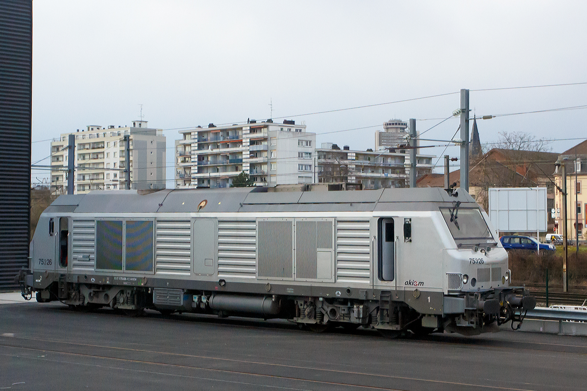 
Die Akiem BB 75 326 (92 87 0075 326-4 F-AKIEM), ex Akiem 75026, ex Fret SNCF 475026, ist am 24.03.2015 bei Muhlhouse (Mülhausen) abgestellt. Die Aufnahme konnte ich aus unserem Zug (TGV) heraus machen.

Die Alstom Prima DE33 B AC (BB 75000) wurde 2007  von Alstom für die Fret SNCF gebaut und als 475026 geliefert. Im Jahr 2011 wurde sie an die SNCF Tochtergesellschaft Akiem S.A.S. (eine französische Leasinggesellschaft für Lokomotiven) übertragen. Im August 2014 wurde sie modifiziert und in 75326 umgezeichnet. 

Durch die Modifizierung kann die Lok für Intercity Nachtzüge verwendet werden, für diese sind die modifizierten Loks der Baureihe BB 75 300 von der SNCF ab Dezember 2015 vorgesehen. Zurzeit sind sie aber noch meist vermietet, wie diese an die CFL Cargo Frankreich.

Die Loks basieren äußerlich weitgehend auf den verwandten Elektroloks der Alstom-Prima-Familie. Von diesen stammen Rahmen, Lokkasten, Führerstände, Drehgestelle, Antriebssystem und die pneumatischen Bremsen. Im Inneren ist viel Technik von Siemens Transportation Systems, von hier kommen die Komponenten Motor-System, Kühlung, Batterie und Hydraulik, welche weitgehend mit denen der Siemens ER 20 BU identisch sind. Aus Kapazitätsgründen werden auch die Kästen von 130 Loks bei Siemens in München gebaut, die Endmontage findet jedoch im Alstom-Werk im französischen Belfort statt, wo auch die restlichen Loks entstehen.

Anzahl:  
99 BB 75000 (davon 7 umgebaut in 75 300)
33 BB 75100 (Deutschland und Benelux tauglich)
167 BB 75400
Spurweite:  1435 mm (Normalspur)
Achsformel:  Bo'Bo'
Länge über Puffer:  20.280 mm
Drehzapfenabstand:  10.820 mm
Dienstmasse:  84 t
Radsatzfahrmasse:  21 t
Höchstgeschwindigkeit:  120 km/h
Installierte Leistung:  2000 kW
Traktionsleistung:  1600 kW
Anfahrzugkraft:  300 kN
Dauerzugkraft: 177 kN bei 32,5 km/h
Treibraddurchmesser:  1.150 mm
Dieselmotor:  MTU 16V 4000 R41 (ab 75401 MTU 16V 4000 R43L)
Tankinhalt:  4000 L
Antrieb:  dieselelektrisch
Fahrmotoren: 4 Stück Asynchronmotoren FRA 4567 6 
Bremse:  elektrische Widerstandsbremse
Kupplungstyp:  Schraubenkupplung
