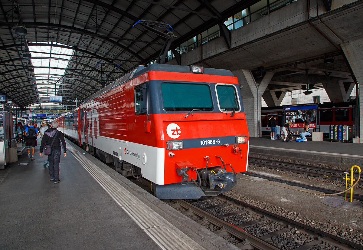 Die HGe 4/4 II die zb HGe 4/4 101 968-6 „Ringgenberg“ (ex SBB Brünigbahn) steht am 09.09.2021 im Bahnhof Luzern mit einem IR nach Engelberg. Führer war die Stammstrecke dieser schmalspurigen gemischte Zahnrad- und Adhäsionslokomotive die Brünigbahn, wo sie aber von einer Vogelschar aus ADLER, FINK und SPATZ Triebzügen verdrängt wurde. 

Die HGe 4/4 101 968-6 wurde SLM (Schweizerische Lokomotiv- und Maschinenfabrik) in Winterthur 1990 unter der Fabriknummer 5402 gebaut, der elektrische Teil ist von ABB, und an die SBB Brünigbahn geliefert (seit 2005 zb). Sie erhielt Prototypdrehgestelle (System Riggenbach), von einer der ehem. Prototyploks SBB 1951 bzw. 1952, den späteren FO 104 und 105.

Die HGe 4/4 II - 101 ist eine schmalspurige (1.000 mm) gemischte Zahnrad- und Adhäsions-Lokomotive. Eine erste Serie von fünf Lokomotiven wurde gemeinsam von der Furka-Oberalp-Bahn (FO) sowie von der SBB für die Brünigbahn, die heute zur Zentralbahn (zb) gehört, beschafft. Da sich dieser Lokomotivtyp bewährte, wurden weitere elf Lokomotiven bestellt, und schließlich gab auch noch die Brig-Visp-Zermatt-Bahn (BVZ) fünf Loks in Auftrag.

Die HGe 4/4 II bespannt vor allem schwere Personenzüge, zum Teil im Pendelzugbetrieb. Bei der Zentralbahn bespannte sie bis 2012 alle Schnellzüge von Meiringen nach Luzern, bei der Matterhorn Gotthard Bahn die Züge des Glacier-Express. Weiter führen die Loks Pendelzüge Brig–Visp–Zermatt und seit der Eröffnung des Tunnels nach Engelberg Pendelzüge Luzern–Engelberg. Außerdem werden aushilfsweise Autopendelzüge durch den Furkatunnel geführt. Schließlich gehören neben weiteren Personenzügen auch diverse Güterzüge Visp–Zermatt sowie bis 2013 Disentis–Sedrun (NEAT-Baustelle) zum Aufgabengebiet.

Konstruktion:
Der Lokomotivkasten ist ein Stahlblechkasten mit gesickten Seitenwänden. Die asymmetrische Frontscheibe aus beheizbarem Verbundglas verbessert die Sicht für den Lokomotivführer. Die drei Dachelemente sind aus Aluminium. Die Pufferkräfte werden über Verstrebungen auf den ganzen Kasten übertragen, weshalb auf seitliche Maschinenraumöffnungen verzichtet werden musste. Der gesamte Kasten hat ein Gesamtgewicht von nur 5,9 Tonnen. Er kann ohne bleibende Deformation eine zentrale Druckkraft von 1000 kN aufnehmen.

Die Drehgestelle sind als geschweißte Hohlträgerkonstruktion mit zwei Längsträgern und einem kräftigen mittleren Querträger sowie zwei Kopftraversen ausgeführt. Sie haben einen Achsstand von 2980 mm, und die Flexicoilfedern stützen den Kasten auf die seitlich an die Längsträger angeschweißten Federwannen. Die Zug- und Druckkräfte werden durch seitlich angeordnete Stangen mit Sphärolastiklagern übertragen. Wegen des kurzen Achsstands sind die Fahrmotoren oberhalb des Drehgestellrahmens angebracht.

Für den Antrieb wurde erstmals der Differentialantrieb eingebaut, der es ermöglicht, im Zahnstangenbetrieb auch einen Anteil der Zugkraft über den Adhäsionsantrieb aufzubringen. Dies setzt wiederum eine Schlupfbegrenzung im Differentialgetriebe voraus, um ein Schleudern oder Gleiten der Räder zu verhindern. Da die zweilamellige Abtzahnstange (System Abt) der FO nicht die gesamte Zugkraft aufnehmen kann, ist die Mithilfe des Adhäsionsantriebs notwendig; dieser übernimmt einen Drittel der Zugkraft. Hätte sich der Antrieb nicht bewährt, wäre es zumindest am Brünig mit der Riggenbachzahnstange möglich gewesen, auf einen abkuppelbaren Adhäsionsantrieb zu wechseln. Dies war aber nicht notwendig, da das Differentialgetriebe zur vollen Zufriedenheit funktionierte.

Bremssysteme:
Dank der elektrischen Rekuperationsbremse ist eine gleichmäßige Beharrungsbremse bei der Talfahrt möglich.
Daneben ist eine normale automatische Druckluftbremse eingebaut, welche auch als Bremssystem I bezeichnet und im Regelbetrieb zum Halten des Zuges verwendet wird. Sie ist als Klotzbremse ausgeführt.
Weiterhin ist noch das Bremssystem II installiert, welches für Zahnradbahnen vorgeschrieben ist und es ermöglichen soll, den Zug nur mit Hilfe der Lokomotive im Zahnstangenabschnitt zum Halten zu bringen, wenn das erste Bremssystem ausfallen sollte. Dieses ist als federspeichergestütztes Bandbremssystem ausgelegt, welches direkt auf das Zahnrad wirkt. Bei Einsatz dieser Bremse treten enorme Kräfte auf, welche nur unter Kontrolle sind, wenn die Anhängelast bei der Talfahrt nicht zu groß ist.
Schließlich ist eine direkt wirkende Rangierbremse vorhanden, die sich der Bremsklötze des Bremssystems I bedient.
Die Lokomotive hat keine Handbremse, sondern wird mit Federspeicherbremsen gesichert.

Technische Daten, der HGe 4/4 II der zb (Brünigbahn), die der FO und BVZ weichen ab:
Spurweite: 1.000 mm
Achsformel: Bo'Bo'
Dienstgewicht: 63 t
Achslast: 16 t
Länge über Puffer: 14'800 mm
Höchstgeschwindigkeit Adhäsion: 100 km/h
Höchstgeschwindigkeit Zahnrad: 40 km/h
Stromsystem: 15 kV 16.7 Hz
Anzahl der Motoren: 4
Antrieb: Gelenkwelle
Antrieb Zahnrad: Differentialantrieb
Zahnradsystem: Riggenbach
Stundenleistung: 1.932 kW
Dauerleistung: 1.875 kW
Anfahrzugkraft: 230 kN (Adhäsion) / 280 kN (Zahnrad)
Anzahl Bremssysteme: 4
Bremsen: Rekuperation, Klotz, Federspeicher, Bandbremse
Anhängelast: 170 t (120 ‰)