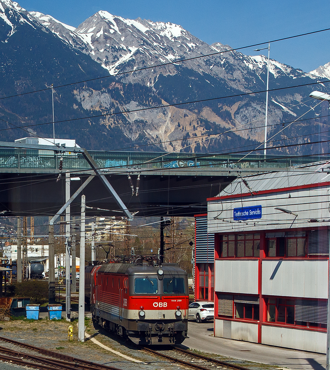 Die �BB 1144 269 (A-�BB 91 81 1144 269-8), ex 1044 269-7. ist am 28.03.2022 beim Hbf Innsbruck abgestellt. Aufgenommen aus einem einfahrenden EC durch die Scheibe.

Die Universallok (ex �BB Reihe 1044) wurde 1994 von der Simmering-Graz-Pauker AG in Graz unter der Fabriknummer 80793 gebaut, die elektrische Ausr�stung ist von ELIN. Sie wurde als 1044 269-7 an die die �BB (�sterreichische Bundesbahnen) geliefert, 2005 erfolgte der Umbau und die Umzeichnung in die heutige �BB 1144 269-8.

Die Universalloks der �BB Reihe 1144 (ehemals Reihe 1044) ist eine elektrische vierachsige Thyristorlokomotive, die sowohl f�r den schweren Schnellzug- als auch G�terzugdienst im Flachland wie auch auf Bergstrecken geeignet ist. Zur Zeit der Indienststellung war sie die st�rkste vierachsige Elektrolok der Welt und bis zur Beschaffung des Taurus das Paradest�ck der �BB. Mit ihrem charakteristischen L�fterger�usch ist sie schon von weitem zu h�ren und dies verlieh ihr den Spitznamen „�sterreichischer Alpenstaubsauger“. Die �BB beschaffte von 1976 bis 1995 von diesen vierachsigen Thyristor-Universallokomotiven 217 St�ck. Die160 km/h schnellen und bis zu 5.120 kW starken vierachsigen Loks pr�gten bis zum Erscheinen der ersten TAURUS-Hochleistungslok das Bild der modernen �BB-Fahrzeugflotte. Die Lokomotiven der �BB Reihe 1044 wurden zur 1144 mit Wendezugsteuerung umger�stet.

Geschichte:
Die bisher verwendeten Wechselstrommotoren waren an einer Leistungsgrenze von 1.000 kW pro Achse angelangt. Aus Schweden wurden erfolgversprechende Entwicklungen gemeldet, bei ihren Rb-Maschinen wurden Gleichstrommotoren mit Stufenschalter und Diodengleichrichter eingebaut. Von der Dioden- zur Thyristorsteuerung war es nur mehr ein kleiner Schritt, den ASEA aus Schweden als erster Elektronikkonzern schaffte. Von einer laufenden Bestellung von schwedischen Rc2 Lokomotiven beschafften die �BB 1971-1974 in zwei Serien insgesamt zehn Lokomotiven der Reihe 1043, die sich von Anfang an bestens bew�hrten.

Dieser Technologiesprung bedeutete einen Paradigmenwechsel im Lokomotivbau, denn nunmehr war es auf Grund der Verwendung von elektronischen Bauteilen m�glich (im Wesentlichen durch eine betr�chtliche Gewichtseinsparung), mehr Leistung auf einem vierachsigen Fahrzeug zu installieren (st�rkerer Transformator und st�rkere Fahrmotoren). Die �BB planten daher eine Beschaffung von je einer gr��eren Serie von G�ter- und Personenzugslokomotiven mit unterschiedlichen Leistungs- und Geschwindigkeitskennwerten. Eine Importl�sung schien nicht ausgeschlossen. Dennoch unterblieb eine solche aus mehreren Gr�nden. 

1974 war es endlich so weit, die �sterreichische Lokindustrie konnte eigene Thyristorlok pr�sentieren. Die zwei Prototyp-Lokomotiven, die 1044.01 und 02 wurden unter anderem mit unterschiedlichen elektronischen Steuerungen ausgestattet. Letztlich bew�hrte sich die 1044.02 und auch die �BB konnten mit der wesentlich h�heren Leistung gegen�ber der 1043 und mit der H�chstgeschwindigkeit von 160 km/h �berzeugt werden. Da die 1044er als Universallok ausgelegt wurden, konnte auch die geplante geteilte Beschaffung f�r den Personen- und G�terverkehr entfallen. Eine „�sterreichische L�sung“ wurde erreicht.

Nach Beseitigung der anf�nglichen Probleme wurden die 1044er mit einer kurzen Unterbrechung bis 1995 weiter gebaut. Die insgesamt 217 Loks wurden von Anfang an grenz�berschreitend bis nach Norddeutschland eingesetzt. Die 1044.01 wurde sogar zur ersten �BB Hochgeschwindigkeitsversuchslok umgebaut und erhielt die Nummer 1044.501. Erst mit der Lieferung der TAURUS-Hochleistungsloks begann ihr Stern ein wenig zu sinken. In den letzten Jahren wurden alle 1044er modifiziert und auch mit einer Wendezugsteuerung ausgestattet. Dadurch sind die nunmehr als 1144 bezeichneten Fahrzeuge noch vielseitiger einsetzbar. Besonders imposant sind die 44er im Einsatz auf der Semmeringbahn, wo sie ihrem Ruf als „�sterreichischer Alpenstaubsauger“ mehr als nur gerecht werden. Man h�rt die Loks schon von weitem und es ist beeindruckend, wie die mittlerweile bis zu 38 Jahre alten Fahrzeuge noch immer unerm�dlich ihren schweren Dienst leisten.

TECHNISCHE DATEN:
Gebaute Anzahl: 217
Baujahre: 1976 bis 1995
Hersteller (mechanisch): SGP Simmering-Graz-Pauker AG (Graz)
Hersteller (elektrisch): BBC (ABB), ELIN, Siemens Wien
Spurweite:  1.435 mm (Normalspur)
Achsformel:  Bo’Bo’
L�nge �ber Puffer:  16.100 mm
Begrenzungslinie: UIC 505-1
Drehzapfenabstand: 8.000 mm
Achsabstand in Drehgestell: 2.900 mm
Raddurchmesser:  1.300 mm (neu) / 1.210 mm (abgenutzt)
Kleinster bef. Halbmesser (V  max= 10 km/h): 120 m 
Dienstgewicht: 84 t
H�chstgeschwindigkeit: 160 km/h (1044.501, ex 1044.01 nach Umbau 220 km/h)
Stundenleistung: 5.280 kW
Dauerleistung: 5.000 kW
Anfahrzugkraft: 340 kN
Dauerzugkraft:  208,9 kN
Stromsysteme: 15kV/16,7Hz AC
Antriebsart: Thyristor-Gleichrichter, Mischstrom-Fahrmotoren mit
Reihenschlu�- (45 %) und Fremderregung (55 %), BBC- Federantrieb
Anzahl der Fahrmotoren: 4
Dynamisches Bremssystem: Elektrodynamische Gleichstrom-Widerstandsbremse
Nenn- / H�chstleistung der dynamischen Bremse:  2.400 / 3.720 kW
Max. Bremskraft der dynamischen Bremse: 115 kN
Bremsbauart: On-GPR-E m Z, ep. / NB� nach „DB-Norm“
Zugheizung: 800 kVA

Quellen: �BB, �BB-Produktion GmbH und Wikipedia
