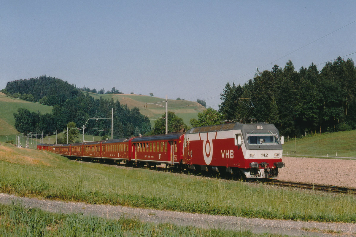 Die Re 456 142 der Vereinigten Huttwil Bahnen VHB mit einem aus zehn Wagen bestehenden Sonderzug bei Gondiswil unterwegs im Sommer 1984. 
Normalerweise war diese starke Lok nur vor schweren Güterzügen zur sehen. 
Kurz nach der Fusion zur RM hat die SOB die Re 456 142-143 angemietet.
Die VHB ist längst Geschichte.
Foto: Walter Ruetsch 
