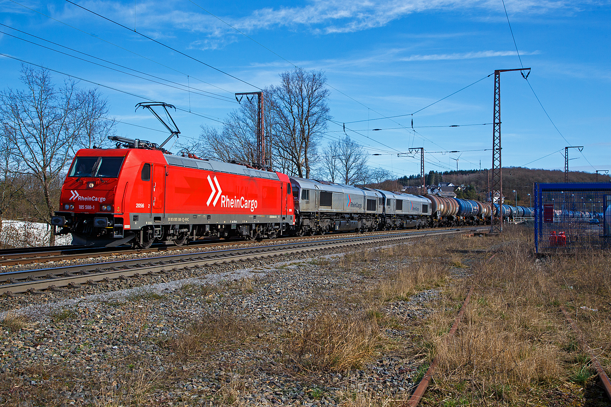 Die RHC 2056 bzw. 185 588-1 (91 80 6185 588-1 D-RHC) der RheinCargo GmbH & Co. KG, ex 2056 (91 80 6185 588-1 D-HGK) der HGK - Häfen und Güterverkehr Köln AG fährt am 20.03.2021, durch Rudersdorf (Kr. Siegen) über die Dillstrecke (KBS 445) in nördlicher Richtung. Im Schlepp bzw. am Haken hat sie die beiden Class 66 (EMD JT42CWR) die RHC DE 670 (92 80 1266 070-2 D-RHC) und die RHC DE 672 (92 80 1266 072-8 D-RHC), sowie einem mit Dieselkraftstoff beziehungsweise leichtes Heizöl (laut Gefahrstofftafel 30/1202) beladenen Kesselwagenzug bestehend aus Wagen der Gattung Zacns

Die RheinCargo ist ein 2012 gegründetes Gemeinschaftsunternehmen der Häfen und Güterverkehr Köln AG und der Neuss-Düsseldorfer Häfen GmbH & Co. KG (NDH), die jeweils zu jeweils 50 % Eigentümer sind. 

Lebensläufe der Loks:
Die TRAXX F140 AC2 (185 588-1) wurde 2008 von Bombardier in Kassel unter der Fabriknummer 34207 gebaut. Zulassungen hat die Lok für Deutschland, Österreich und die Schweiz, sie hat auch vier Stromabnehmer. Eigentlicher Eigentümer ist die AKIEM SAS, die zum 23.04.2020 das Leasinggeschäft für Schienenfahrzeuge von der Macquarie European Rail Limited (Luxembourg), ehemals CBRail übernommen hat.

Die beiden EMD JT42CWR (auch bekannt als Class 66) wurde 2003 von EMD (Electro-Motive Division eine Tochter von General Motors) gebaut, die RHC DE 670 (92 80 1266 070-2 D-RHC), ex HGK DE 170, unter der Fabriknummer 20028453-3 und die DE 672 (92 80 1266 072-8 D-RHC), ex HGK DE 172, unter der Fabriknummer 20028453-5. Eigentümer und Vermieter der beiden Class 66 ist die Beacon Rail Leasing Ltd in London, bis zum Verkauf zum 01.01.2007 war  es die HSBC Rail Ltd., London.