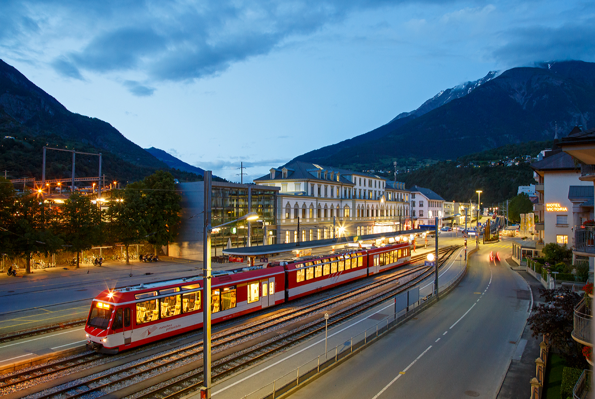 Ein abendlicher Blick vom Balkon des Hotels Europe in Brig am 19.06.2016, auf den Bahnhof Brig. Vorne der Bahnhofvorplatz mit den Gleisen und Bahnsteigen der MGB, wo gerade der  KOMET  ABDeh 4/8 - 2022 als RB nach Zermat h�lt. Hinten das Empfangsgeb�ude vom SBB Bahnhof.