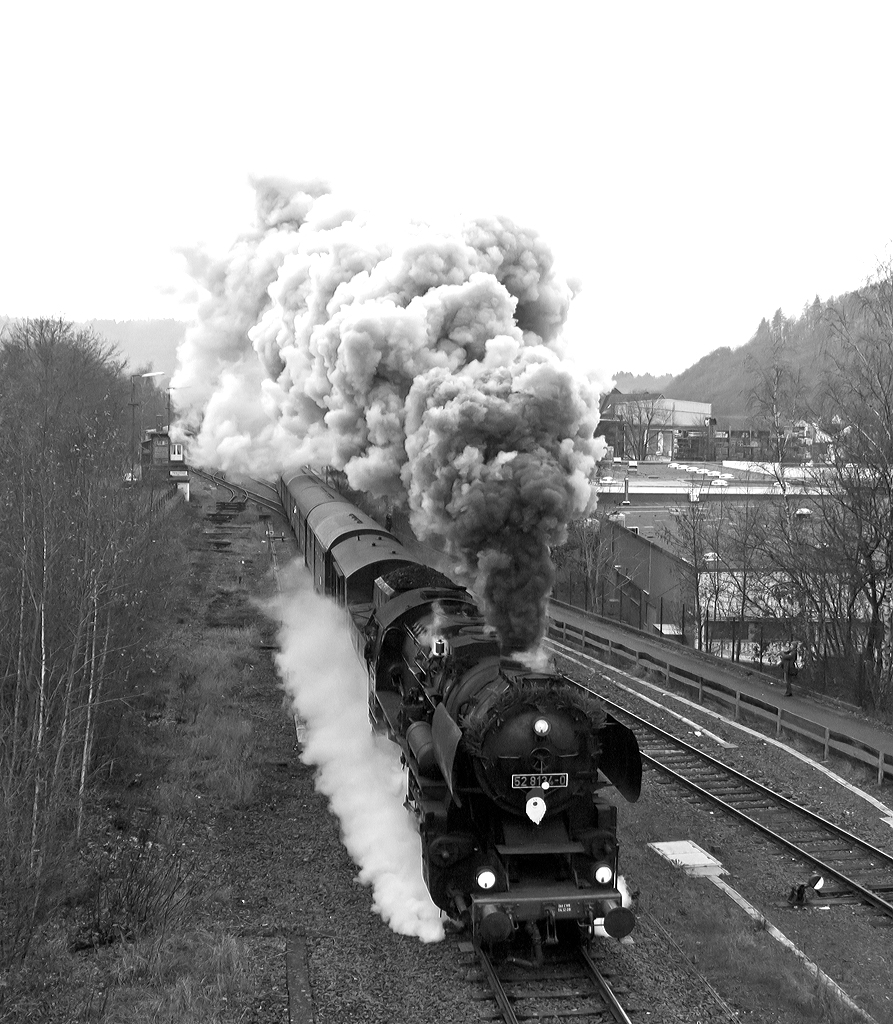 
Hier nochmals, in der schwarz-weiß Version....
Mit einer mächtigen Rauchfahne durchfährt die Betzdorfer  52 8134-0 (ex DB 052 134-4, ex DR 52 8134-0) am 30.11.204 Herdorf, hier kurz hinter dem Bahnhof bzw. kurz vor der Brücke Wolfsweg. 

Heute veranstalten die Eisenbahnfreunden Betzdorf ihre alljährlichen Nikolausfahrten zwischen Betzdorf/Sieg und Würgendorf auf der Hellertalbahn (KBS 462).