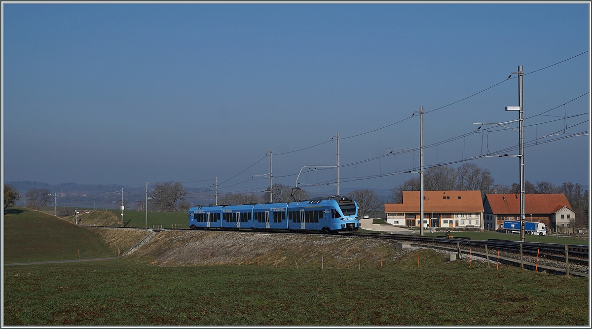 In weiten Kurven windet sich das Trasse der Strecken von Romont nach Vuisternens-devant- Romont, um die gut achzig Höhenmeter zu überwinden. Der im sehr gefälligen Werbeanstrich der  Groupe Grisoni  gehaltene TPF RABe 527 198 hat die Steigung fast geschafft und erreicht in Kürze den Bahnhof Vuisternas-devant-Romont, welcher jedoch wie alle Station zwischen Romont und Bulle nur noch dienstlichen Zwecken dienen.

1. März 2021