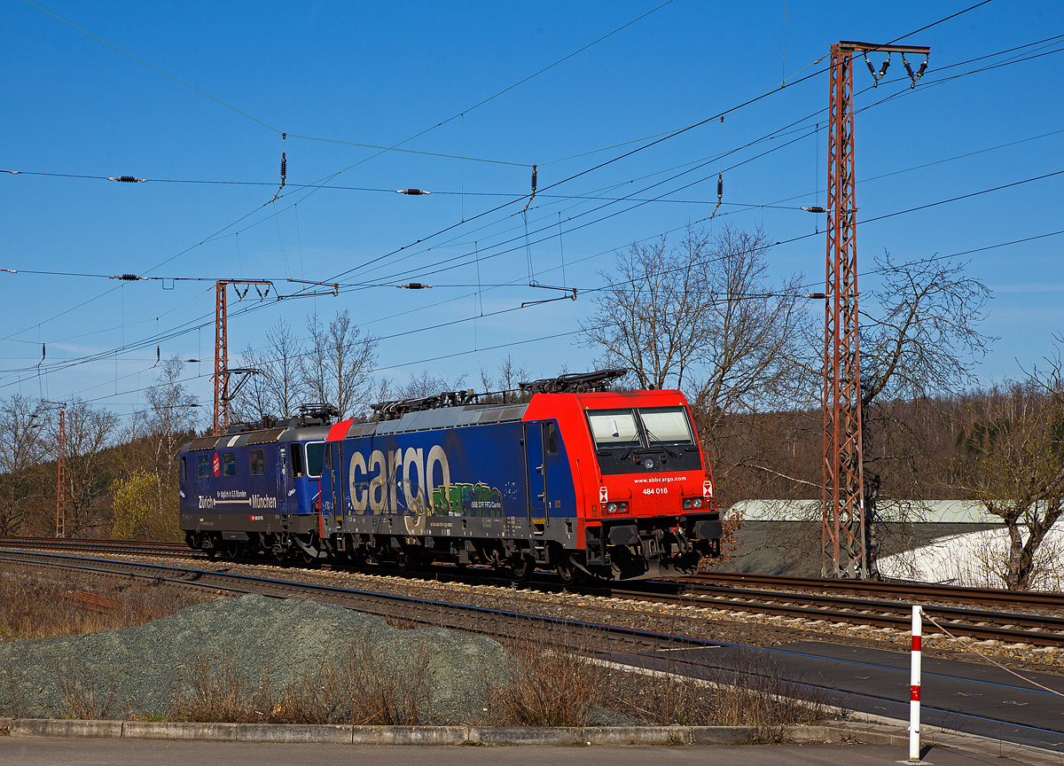 Ja, „Gr�ezi“ oder „Servus“.....
Die SBB Cargo Re 421 371-6 (91 85 4421 371-6 CH-SBBC), ex Re 4/4 II 11371, mit Werbung Z�rich – M�nchen 6 x t�glich in 3,5 Stunden, f�hrt am 30.03.2021 mit der SBB Cargo Re 484 016-1(91 85 4484 016-1 CH-SBBC), ex E 484.016 SR, einer TRAXX F140 MS am Haken durch Rudersdorf (Kr. Siegen), an der Dillstrecke (KBS 445), in Richtung Siegen.

Eine SBB Cargo Re 484 wie die 016-1 kann man eigentlich Deutschland nur mit viel Gl�ck sehen, denn sie haben nur die Zulassungen f�r die Schweiz und Italien. Sie haben keinen Stromabnehmer mit breiterer Wippe gem�� deutscher Vorschrift, auch die die deutsche Zugsicherung Indusi fehlt ihnen. Der Lz war auf dem weg nach Krefeld.

Lebensl�ufe:
Die Re 421 371-6 wurde 1983 von der SLM Winterthur (Elektrik BBC/ SAAS) unter der Fabriknummer 5235 gebaut und als Re 4/4 II 11371 an die SBB geliefert. Im Jahr 2002 erfolgte der Umbau zur Re 421 f�r die SBB Cargo (Einsatz auch in Deutschland). Die zugelassene H�chstgeschwindigkeit f�r die Schweiz betr�gt 140 km/h und f�r Deutschland 120 km/h.

Die Re 484 016-1 eine Bombardier TRAXX F140 MS wurde 2004 von Bombardier in Kassel unter der Fabriknummer 34009 gebaut und an die SBB Cargo AG, als E 484.016 SR geliefert. 
