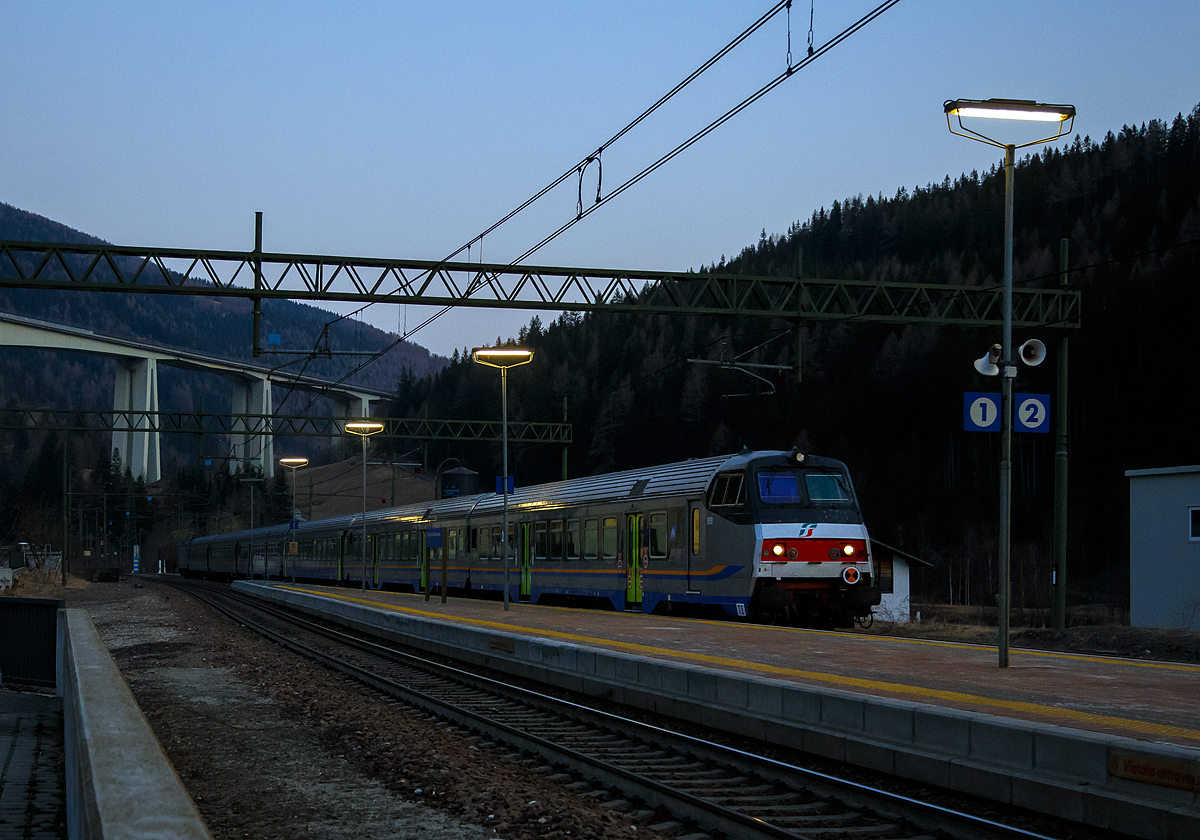 Sehr sauber und Steuerwagen voraus erreicht der Trenitalia Regional-Express RE 3462 (Verona Porta Nuova – Trento – Bozen – Brenner/ Brennero) am Abend des 27.03.2022 um 18:45 Uhr (noch ist Winterzeit) den Bahnhof Gossensaß/Colle Isarco, Schublok war die E.464.562.

An der Spitze ein 2. Klasse Reisezug- MDVC-Steuerwagen mit Gepäckabteil (MDVC steht für Medie Distanze Vestiboli Centrali, deutsch für Mittlere Entfernungen in Ballungsräumen) der Gattung npBD. Bei diesen Wagen handelt es sich um in Italien hergestellte Eisenbahnwaggons die speziell für den Einsatz für mittlere Entfernungen wie z.B. RE (Regionalexpress Züge). Das „TE“ (vorne unten zeigt das es sich um einen Steuerwagen vom Typ TE (Tipo TE) für E-Loks handelt.