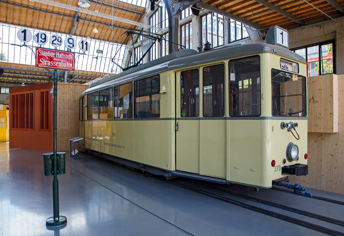
Triebwagen 378 vom Typ DUEWAG  „Verbandstriebwagen T2“ der Rheinischen Bahngesellschaft AG (heute Rheinbahn AG) ausgestellt im Verkehrszentrum des Deutschen Museums (am 16.06.2018) in M�nchen (Theresienh�he).

Der zweiachsige Triebwagen vom Typ „Verbandswagen“ wurde 1950 in einer Serie von 30 St�ck bei der D�sseldorfer Wagenbau  Gesellschaft (D�WAG) f�r die Rheinische Bahngesellschaft AG gebaut. Die Initiative f�r den Bau des Zweirichtungsfahrzeuges in Einheitsbauweise ging vom „Verband �ffentlicher Verkehrsbetriebe“ aus. Er gab dem Fahrzeug seinen Namen.

Die Konstruktion dieses Triebwagens geht auf die Entwicklung eines modernen Stra�enbahnwagens in der Mitte der 1930er Jahre zur�ck. Hauptmerkmale waren ein Wagenkasten aus Ganzstahlbauweise, ein geschwei�tes Fahrgestell und ein niedriger Fu�boden. Dieser „Niederflurwagen“ konnte sich in der Zeit des 2. Weltkrieges nicht weiter entwickeln. Stattdessen baute man w�hrend des Krieges mit einfachen Materialien, aber modernen Merkmalen wie gro�en einteiligen Fenstern oder einem Sitz f�r den Fahrer den sogenannten „Kriegsstra�enbahnwagen“. Nach dem Krieg nutze die Rheinbahn die Gestelle zerst�rter Wagen des „Niederflurtyps“, um auf ihnen neue Wagen aufzubauen. Dieser „Aufbauwagen“ vereinte die modernen Elemente des „Kriegsstra�enbahnwagens“ mit dem Gestell des „Niederflurwagens“ und wirkte durch die tief heruntergezogenen Seiten, die das Fahrwerk verdeckten deutlich moderner.

Der neu gebaute Wagen des „Verbandstyps“ der Rheinbahn entsprach bis auf wenige �nderungen fast vollst�ndig seinem Vorl�ufer und ist das letzte zweiachsige Stra�enbahn-Fahrzeug, das in Deutschland gebaut wurde. Die Rheinbahn beschaffte 30 Triebwagen und 64 Beiwagen des Verbands- bzw. Aufbau-Typs. 

TECHNISCHE DATEN:
Spurweite: 1.435 mm (Normalspur)
Achsformel: B
L�nge; 10.500 mm
Leergewicht: 18.900 kg
Leistung: 2 x 75 kW
H�chstgeschwindigkeit: 60 km/h
Stromsystem: 600 V DC (Oberleitung)
Sitzpl�tze: 	22
Stehpl�tze: 46
