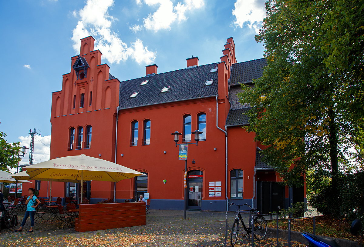 
Von der Straßenseite das Empfangsgebäude des Bahnhofs Schladern (Sieg) an der Siegstrecke im Ort Windeck-Schladern am 07.09.2020. Das im wilhelminischen Stil 1859 erbaute Ziegelgebäude steht unter Denkmalschutz.

Schlosskopie mit eigener Geschichte
Ohne Bahn kein Fortschritt. Erst mit der Bahnlinie zwischen Köln und Gießen durch das Siegtal konnte die Industrie an der Sieg von der wachsenden Wirtschaft der Industrialisierung profitieren. 1860 erhielt Schladern einen eigenen Bahnhof, der schwierigen Streckenführung durch Berge und über den Fluss zum Trotz. Doch der Aufwand lohnte sich, denn Schladern gehörte Damals zum Kreis Waldbröl und sein Bahnhof war bald Hauptumschlagplatz für Waren aus dem Oberbergischen Land. Der Bahnhof mit seinem repräsentativen Empfangsgebäude erinnert dabei auch an eine Zeit, in der man die reiselustigen Großstädter vom Rhein angemessen willkommen hieß. Mit seinem Baustil und den abgestuften Giebeln war die Ähnlichkeit des Baus mit dem ehemaligen Schloss Windeck durchaus gewollt.

Doch obwohl bereits 1870 mit der Gründung der Bröltaler Eisenbahn (Bröltalbahn) zwischen Hennef (Sieg) und Waldbröl (ab 1891 auch ab Bonn-Beuel) ein Großteil des Warenumschlages auf die neue Schmalspurbahn (Spurweite 785 mm) überging, siedelte sich rund um dem Bahnhof Schladern Industrie an: ein Ziegelwerk, ein Eisenwerk und ein großes Kupferwerk mit eigenem Gleisanschuss (zuletzt als Firma „kabelmetal“ bekannt). Mit dem Rückgang des Güterverkehrs auf der Schiene in den 1990er Jahren und dem Aus für „kabelmetal“  nahm die Bedeutung des Bahnhofs Schladern für den Güterverkehr ab, während es für Pendler (meist in den Großraum Köln) immer wichtiger wurde. Das seit 1989 unter Denkmalschutz stehende Empfangsgebäude wurde aufwendig saniert und restauriert.

Quelle: Am Gebäude angebrachte Tafel