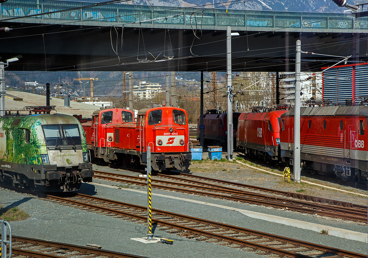 Zwei Verschubloks Methusalem der ÖBB Reihe 2067 (SGP LDH 600) abgestellt am 28.03.2022 beim Hbf Innsbruck, vorne die ÖBB 2067 101-2, dahinter eine weitere 2067 107-9, aufgenommen aus einem einfahrenden EC durch die Scheibe.

Vorne die 2067 101-2 wurde 1975 von SGP (Simmering-Graz-Pauker) im Werk Wien-Floridsdorf  (ex WLF) unter der Fabriknummer 18515 gebaut und als 2067.101 an die ÖBB (Österreichische Bundesbahnen) geliefert. 1985 erfolgte die Umzeichnung in ÖBB 2067 101-2. Die 2067 107-9 wurde 1977 von SGP (Wien) unter der Fabriknummer 18532 gebaut und als 2067.107 an die ÖBB (Österreichische Bundesbahnen) geliefert. 1985 erfolgte die Umzeichnung in ÖBB 2067 107-9.

Geschichte:
Nachdem sich Ende der 1950er Jahre die zweiachsigen Dieselloks der Reihen 2060 und 2062 für viele Aufgaben als zu schwach erwiesen, wurde von der Firma SGP (Simmering-Graz-Pauker, Werk Wien-Floridsdorf, ex WLF) die 600 PS starke, dreiachsige Baureihe 2067 (SGP LDH 600) entwickelt. Der Motor basiert auf dem Viertakt-Zwölfzylinder vom Typ SGP S12a. Die Kraftübertragung erfolgt über ein hydraulisches Voith-Getriebe (Typ L28St) auf eine Blindwelle die durch Stangenantrieb mit den drei Achsen verbunden war. Von 1959 bis 1977 wurden insgesamt 111 Lokomotiven von den ÖBB übernommen. Die Lokomotiven bis zur Ordnungsnummer 31 hatten einen kleineren Schalldämpfer (mit dementsprechend lauterem Motorengeräusch) und einen anderen Vorbau. 2001 wurde mit der Ausmusterung von Serienmaschinen begonnen, welche sich bis heute hinzieht. Vereinzelt werden sie noch für kleine Verschübe und Tunnelrettungszüge eingesetzt. 2020/2021 sind offiziell noch 10 Loks im aktiven Bestand inklusive 2067 001 und 003.

Konstruktion und Technik:
Der Lokrahmen besteht aus starken Längsblechen – diese sind mit Querträgern zu einem Kastenträger zusammengeschweißt. Auf diesem Rahmen sitzt die Antriebsanlage, die sich neben anderen wichtigen Aggregaten in dem längeren Vorbau befindet. Daran schließen das Führerhaus und ein kürzerer Vorbau an. Das Führerhaus und die beiden Vorbauten wurden in geschweißter Blechkonstruktion ausgeführt. Ab 2067 032 wurden die Klappen in Motornähe gegen Schiebetüren getauscht, was die Zugänglichkeit zum Motor erleichterte. Die Radsätze lagern bei den Loks bis 2067.81 in Gleitlagern in Ausnehmungen des Rahmens, ab 2067.82 hat man Rollenlager verwendet. Die Kraftübertragung erfolgt über die Kuppelstangen auf alle drei Achsen. Bis zur 101. Serienlok wurde das Führerstandseitenfenster als Schiebefenster ausgeführt. Die letzte Serie von 1977 von 102-111 bekamen kurbelbare Senkfenster. Viele Loks der anderen Serien wurden auf solche Fenster umgebaut. Teilweise wurde auch das fixe Fenster in der Tür gegen ein Übersetzfenster getauscht, welches die letzte Serie ebenso serienmäßig besaß.

Die Motorenkonstruktion (Typ SGP 12a) wurden von den Baureihen 2045 und 5145 übernommen. Nur wurde die Drehzahl auf 1500/min erhöht. Im Laufe der Produktion wurde eine weiterentwickelte Variante eingebaut. Die neue Bezeichnung lautete SGP S12na. Bei ein paar Loks wurde der SGP S12a gegen den SGP S12na getauscht. 13 Loks wurden in den 1990er Jahren remotorisiert und erhielten Caterpillar-Motoren. Von diesen Loks existierten 2020 noch sechs Loks.

Die Kraftübertragung vom Motor erfolgt über eine Welle auf ein hydraulisches Turbogetriebe (Zwei-Wandler-Turbogetriebe) vom Typ Voith L28/III/4-1.6 St-09, das eine Blindwelle antreibt. Die mittlere Achse ist bei der Serie 62-71 mit einem geschwächten Spurkranz, bei allen anderen seitenverschiebbar ausgeführt. Alle Loks der Baureihe 2067 verfügen über eine selbsttätige und eine nicht selbsttätige Druckluftbremse, und eine Einfache Sifa. Eine PZB ist in der Originallok nicht vorhanden, aufgrund geänderter Vorschriften wurde im TS Werk Linz 2008/2009 Versuchsweise die 2067.107 mit einer I60 nachgerüstet. Alle noch vorhandenen gewesenen Loks der jüngeren Serien und 2067.04 des Ösek bekamen ebenso eine I60. Einige bekamen auch den GSM-R-Funk.

TECHNISCHE DATEN:
Gebaute Anzahl: 112
Hersteller: SGP (Simmering-Graz-Pauker, Werk Wien-Floridsdorf, ex WLF)
Baujahre: 1959 bis1977
Spurweite:  1.435 mm (Normalspur)
Achsformel:  C
Länge über Puffer:  10.484 mm
Begrenzungslinie: UIC 505-1
Achsabstände: 4.300 mm (1.650 mm / 2.650 mm)
Raddurchmesser:  1.140 mm (neu) / 1.070 mm (abgenutzt)
Dienstgewicht: 49 t
Max. Radsatzlast : 16,2 t
Dieselmotor: 12-Zylinder-Viertakt- Dieselmotor vom Typ SGP S12na 
Nenndrehzahl des Dieselmotors: 720 – 1.500 U/min
Leistung: 442 kW (600 PS)
Anfahrzugkraft: 148 kN
Getriebe: Zwei-Wandler-Turbogetriebe vom Typ Voith L28/III/4-1.6 St-09
Zugelassene Höchstgeschwindigkeit: 65 km/h
Kleinster Krümmungsradius (v max= 10 km/h): R 80 m
Tankinhalt : 1.600 l
Bremsbauart: On-GP m Z

Quellen: ÖBB, ÖBB-Produktion GmbH und Wikipedia
