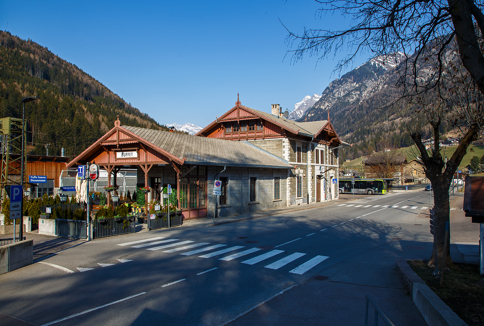 Blick auf den Bahnhof Gossensaß/Colle Isarco am 26.03.2022.
Der Bahnhof Gossensaß (auch Gossensass; italienisch Stazione di Colle Isarco) befindet sich an der Brennerbahn in Südtirol (italienisch Alto Adige), amtlich Autonome Provinz Bozen – Südtirol.

Der Bahnhof Gossensaß ist der erste Haltepunkt im Wipptal südlich des Brennerpasses, zu dem die Bahnstrecke von hier aus über den Pflerschtunnel ansteigt. Er liegt auf 1.066,9 m Höhe nahe dem Zentrum von Gossensaß, dem Hauptort der Gemeinde Brenner, und der durch das Dorf führenden SS 12 (der alten Brennerpass-Straße). 

Der Bahnhof wurde 1867 zusammen mit dem gesamten Abschnitt der Brennerbahn zwischen Innsbruck und Bozen in Betrieb genommen. Durch ihn erlebte Gossensaß bis zum Ersten Weltkrieg seine Blütezeit als bekannter Touristenort. Er konkurrierte mit Orten wie St. Moritz oder Chamonix. 

Das Aufnahmegebäude war zunächst noch relativ kompakt gehalten, wurde wegen der vielen Touristen jedoch noch im 19. Jahrhundert durch einen südlichen Anbau erweitert. Das ursprüngliche Gebäude weist eine Verkleidung aus Grauwacke auf, während dekorative Details wie die Fensterfassungen in weißem Kalkstein gehalten sind. Straßenseitig ist es durch einen in sorgfältigen Details gearbeiteten Dachgiebel aus Holz gestaltet. Der Anbau ist in Brixner Granit gemauert und sticht durch eine hölzerne Veranda hervor. In dem sich heute das Buffet befindet und man auch den Espresso genießen kann. Das Gebäude steht seit dem Jahr 2000 unter Denkmalschutz.

Der Bahnhof Gossensaß wird durch Regionalzüge der Trenitalia sowie der SAD bedient, die auch Busverbindungen zum Bahnhof betreibt. Die Regionalzüge fahren in beide Richtung (Brenner bzw. Bozen) im Stundentakt und werden zu Hauptverkehrszeiten durch Regionalexpresszüge verdichtet.

Uns hat es in Gossensaß sehr gut gefallen, es war einfach zu kurz, so dass wir gerne wiedermal dort hinfahren wollen. Für die drei Tage haben wir uns ein Südtirol/Alto Adige Ticket (eine Mobilcard für 3 Tage) am Automat für 23,00 Euro geholt. So konnten wir mit diesem Ticket Südtirol mit der Bahn erkunden. 