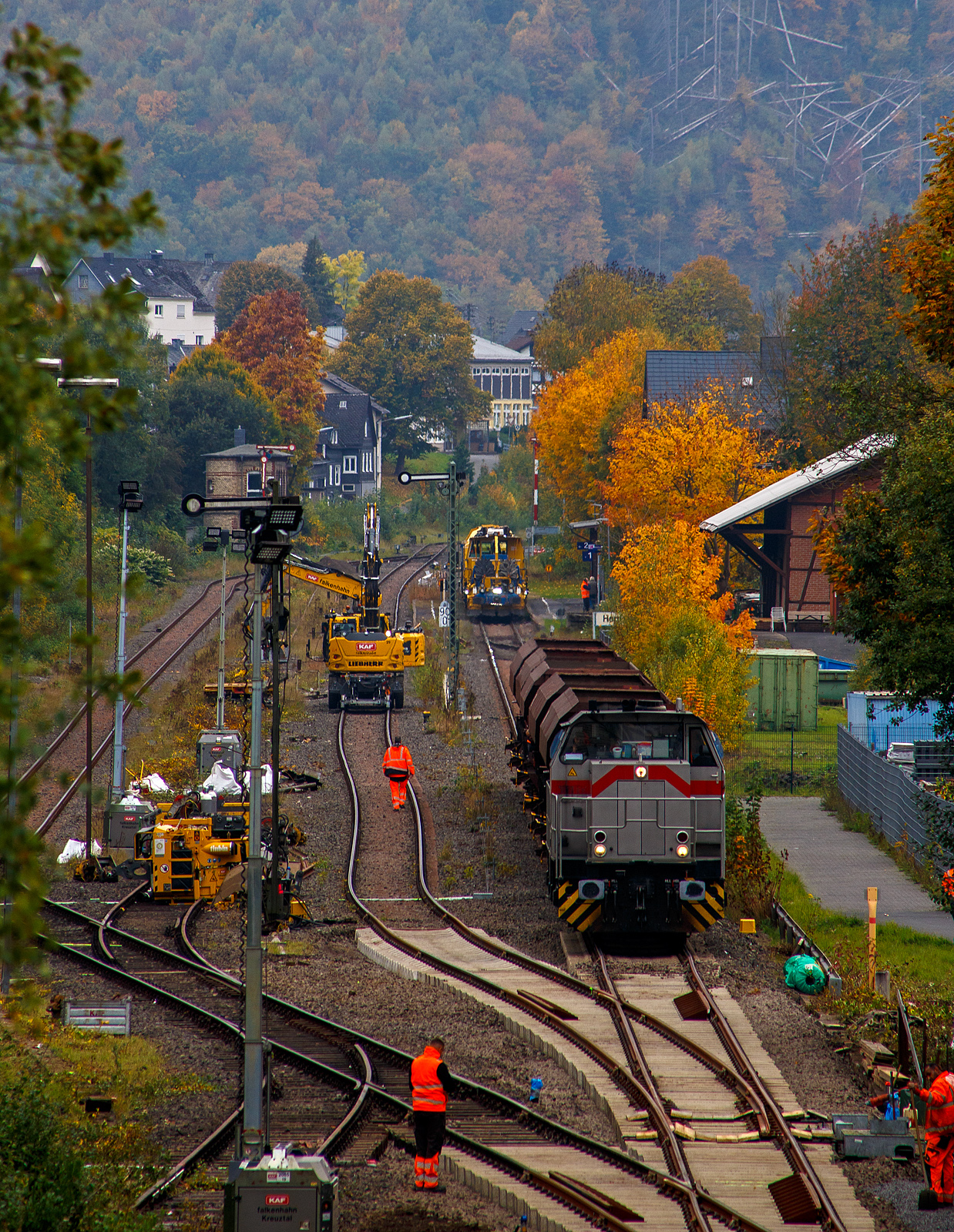 Blick auf den Bahnhof Herdorf und die Baustelle in Blickrichtung Betzdorf am 12 Oktober 2025. Die Weichen 25 und 26 sind beide eingebaut, müssen noch eingeschottert werden.

So steht die 277 809-0  Elmi“ (92 80 1277 809-0 D-KAF), eine Vossloh MaK G 1700 BB der KAF - Falkenhahn Bau AG (Kreuztal), steht mit einem Schotterzug bereit. Hinten beim Bahnhof haben die Schnellschotterplaniermaschine SSP 110 SW, Schweres Nebenfahrzeug Nr. 99 80 9425 068-0 D-DGU und die Universalstopfmaschine UNIMAT 09-475/4S, Schweres Nebenfahrzeug Nr. D-DGU 99 80 9424 001-2, den Bahnhof erreicht müssen aber nach das Einschottern abwarten. Beide Plasser & Theurer Maschinen gehören der Deutsche Gleisbau Union GmbH & Co. KG (DGU), Koblenz