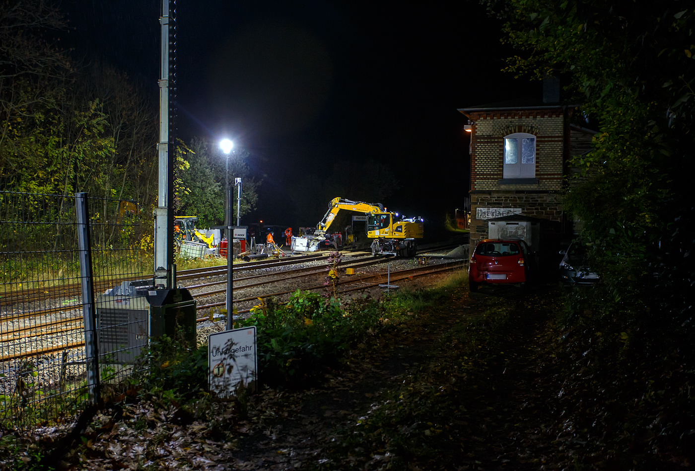 Blick auf die Baustelle Bahnhof Herdorf am Abend des 26 Oktober 2025 (21:30 Uhr). Der Liebherr Zweiwegebagger A 922 Rail Litronic mit Abst�tzpratzen, Kleinwagen Nr. D-KAF 99 80 9904 795-8 (KAF Interne Nr. 10016), der KAF Falkenhahn Bau AG (Kreuztal), r�umt schonmal die Baustelle. Zwischen den Gleisen gelagertes Material wird auf den Lagerplatz gehoben, wo es dann einem Radlader an entsprechende freie Stellen umgesetzt wird.  