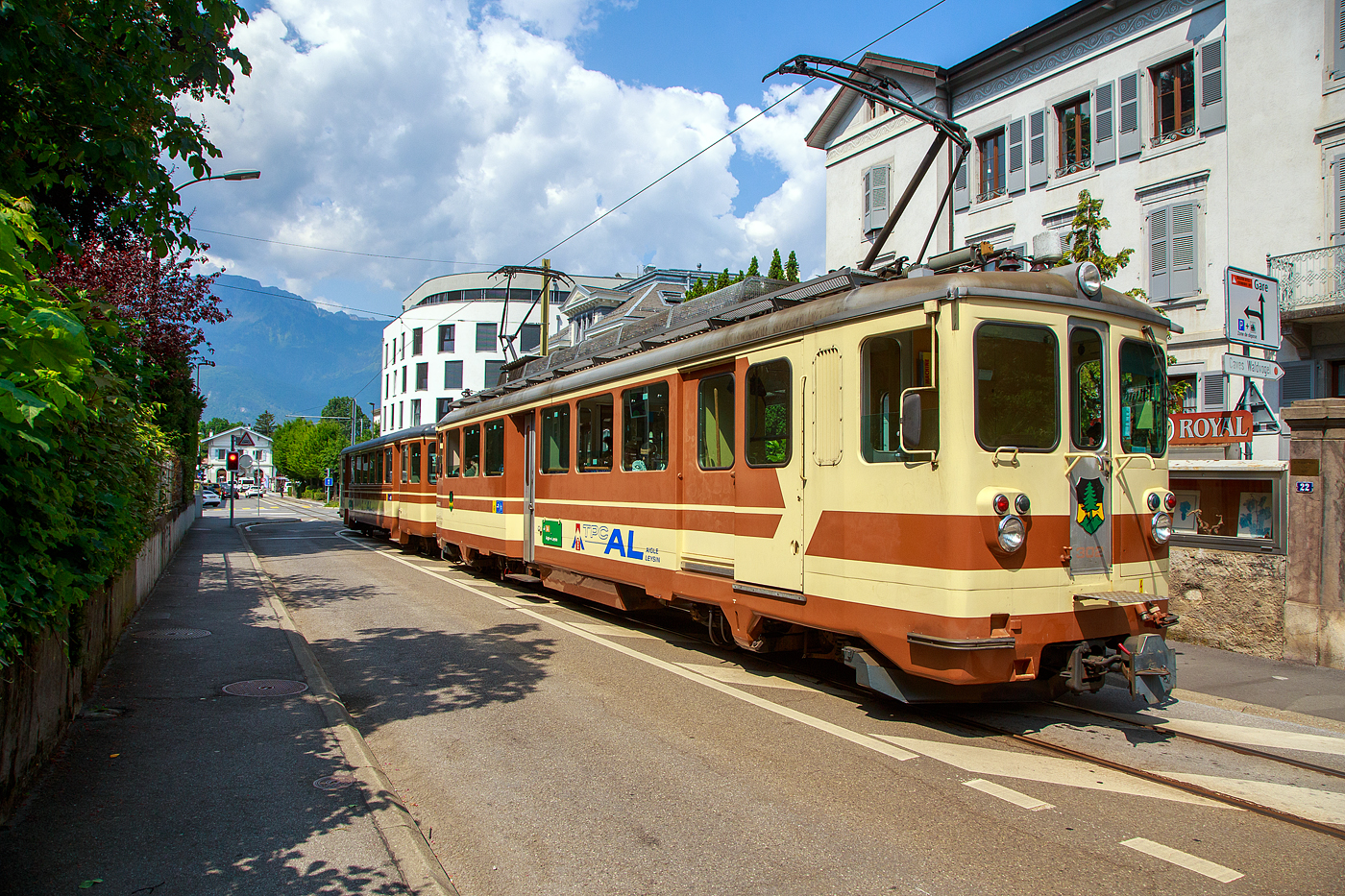 Der AL Regionalzug von Leysin nach Aigle fährt am 28. Mai 2023 (hier als Straßenbahn) durch Altstadt und erreicht bald den Bahnhof Aigle. Der Zug besteht aus dem führenden Steuerwagen AL Bt 351 „Aigle“  und dem Triebwagen AL BDeh 4/4 302 „Leysin“, beide sind noch im ursprünglichen Anstrich der AL (es sind auch die einzigen). 

In Aigle (Waadt) gibt es gleich drei Schmalspurbahnen, die seit 1999 in die Transports Publics du Chablais (TPC) fusioniert worden sind, so machten wir auf unserer Rückreise hier mal einen kurzen Zwischenhalt. Die Schmalspurbahnen sind die Aigle–Ollon–Monthey–Champéry-Bahn (AOMC), die Aigle–Sépey–Diablerets-Bahn (ASD), seit dem 22. Dezember 1913 und die Aigle–Leysin-Bahn (AL).

Die Chemin de fer Aigle–Leysin (AL), deutsch Aigle-Leysin-Bahn, war eine Eisenbahngesellschaft im Schweizer Kanton Waadt. Ihre von 1900 bis 1916 eröffnete 6,2 Kilometer lange Strecke führt von Aigle im Rhonetal hinauf nach Leysin-Grand Hôtel. Die gemischte Zahnradbahn in der Spurweite 1.000 mm (Meterspur) mit dem System Abt wird seit der Betriebsaufnahme elektrisch betrieben. Im Jahr 1999 fusionierte die AL zu den Transports Publics du Chablais (TPC).

Die Bahnstrecke Aigle–Leysin hat ihren Ausgangspunkt vor dem SBB-Bahnhof und führt als Straßenbahn auf der Rue de la Gare (Bahnhofstraße), der Avenue des Ormonts und über die Grande Eau zum Kopfbahnhof Aigle-Dépôt. Dort ändern die Züge die Fahrtrichtung, damit das Triebfahrzeug für die anschließende Bergfahrt am Ende des Zuges eingereiht ist. 

Im Keilbahnhof Aigle-Dépôt beginnt der 5,3 Kilometer lange und bis zu 230 Promille steile Zahnstangenabschnitt. Zunächst führt er durch die Rebberge und bietet den Fahrgästen einen Ausblick auf das Rhonetal. Bei der Haltestelle Pont-de-Drapel wechselt die Vegetation und das Trassee befindet sich nun im Wald. Der Zug erreicht eine Waldlichtung mit dem Bahnhof Rennaz (Leysin), wo er sich in der Regel mit dem Gegenzug kreuzt. Die Strecke führt weiter durch Wald und den 154 Meter langen Tunnel Rennaz. Ab rund 1.200 Meter über Meer fährt die Zahnradbahn durch Weiden und erreicht nach kurzer Zeit den Bahnhof Leysin-Village (Leysin-Dorf). Hier beginnt der Doppelspurabschnitt mit der 128 Meter langen Brücke Leysin nach Leysin-Feydey. Nach dem 287 Meter langen Kehrtunnel Leysin erreicht die Strecke, immer noch mit Zahnstange versehen, den Endpunkt Leysin-Grand Hôtel.


Die Triebwagen und Steuerwagen BDeh 4/4 301–302 und Bt 351–352 wurden 1966 von SIG/SAAS gebaut. 

TECHNISCHE DATEN:
Spurweite: 1.000 mm
Fahrleitungsspannung: 1.500 V =

Triebwagen: BDeh 4/4 301-302
Zahnstangensystem: Abt
Achsfolge: Bo'zz Bo'zz
Länge über Puffer: 16.100 mm
Drehzapfenanstand: 9.540 mm
Achsabstand im Drehgestell: 2.460 mm
Leistung: 596 kW (808 PS)
Treibraddurchmesser: 840 mm (neu)
Zahnrad-Teilkreisdurchmesser: 650
Höchstgeschwindigkeit: 40 km/h
Übersetzung: 1:12,2
Gewicht: 33.0 t
Sitzplätze: 48
Max. Ladegewicht: 1,5 t

Steuerwagen Bt 351–352
Anzahl der Achsen: 4
Gewicht: 11.0 t
Sitzplätze: 48
