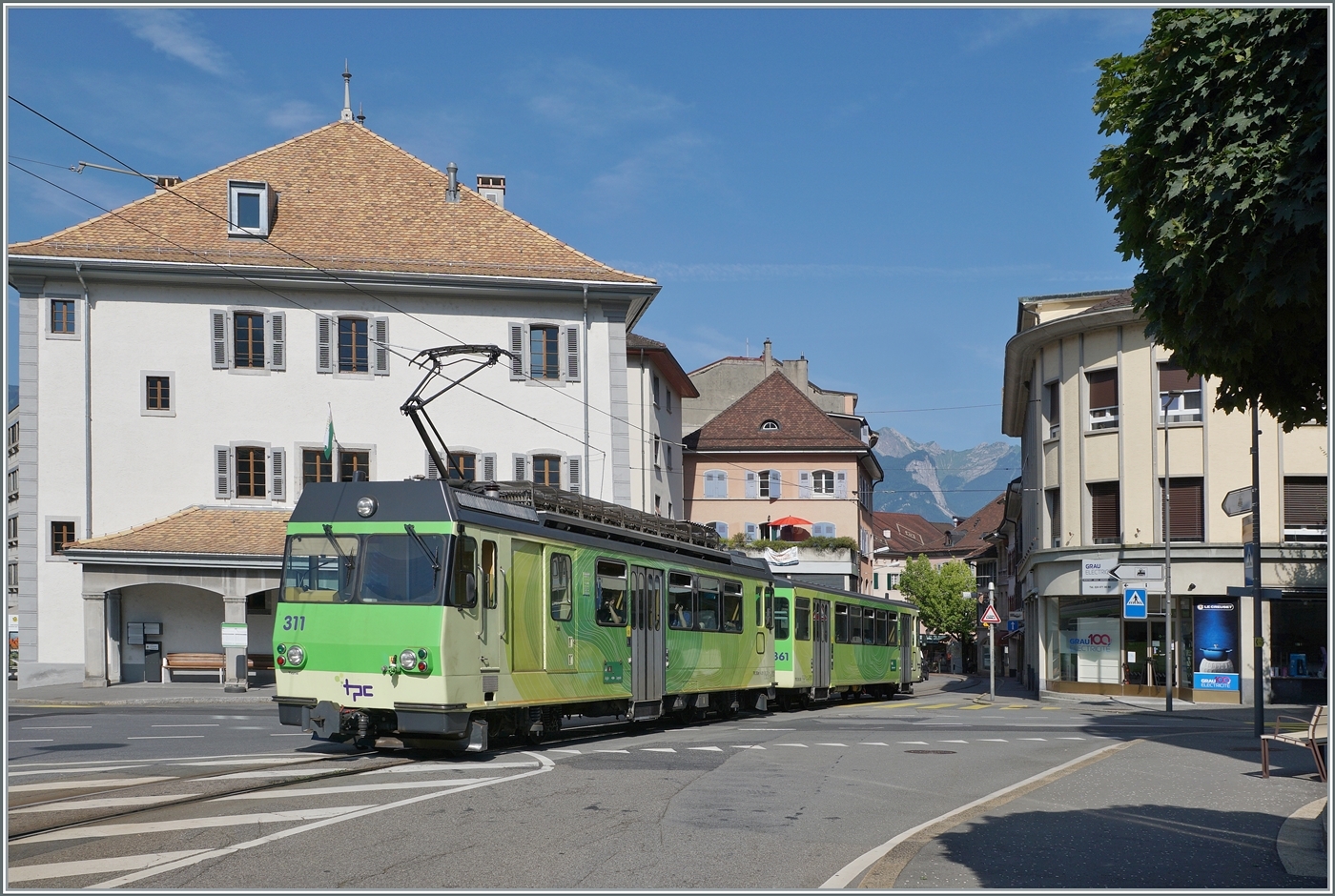 Der BDeh 4/4 311 mit seinem Bt 363 ist auf der Fahrt zum Bahnhof von Aigle und erreicht hier die Altstadt von Aigle, wo das Trasse der Bahn mitten auf der Strasse durch die engen Gassen führt.

27. Juli 2024