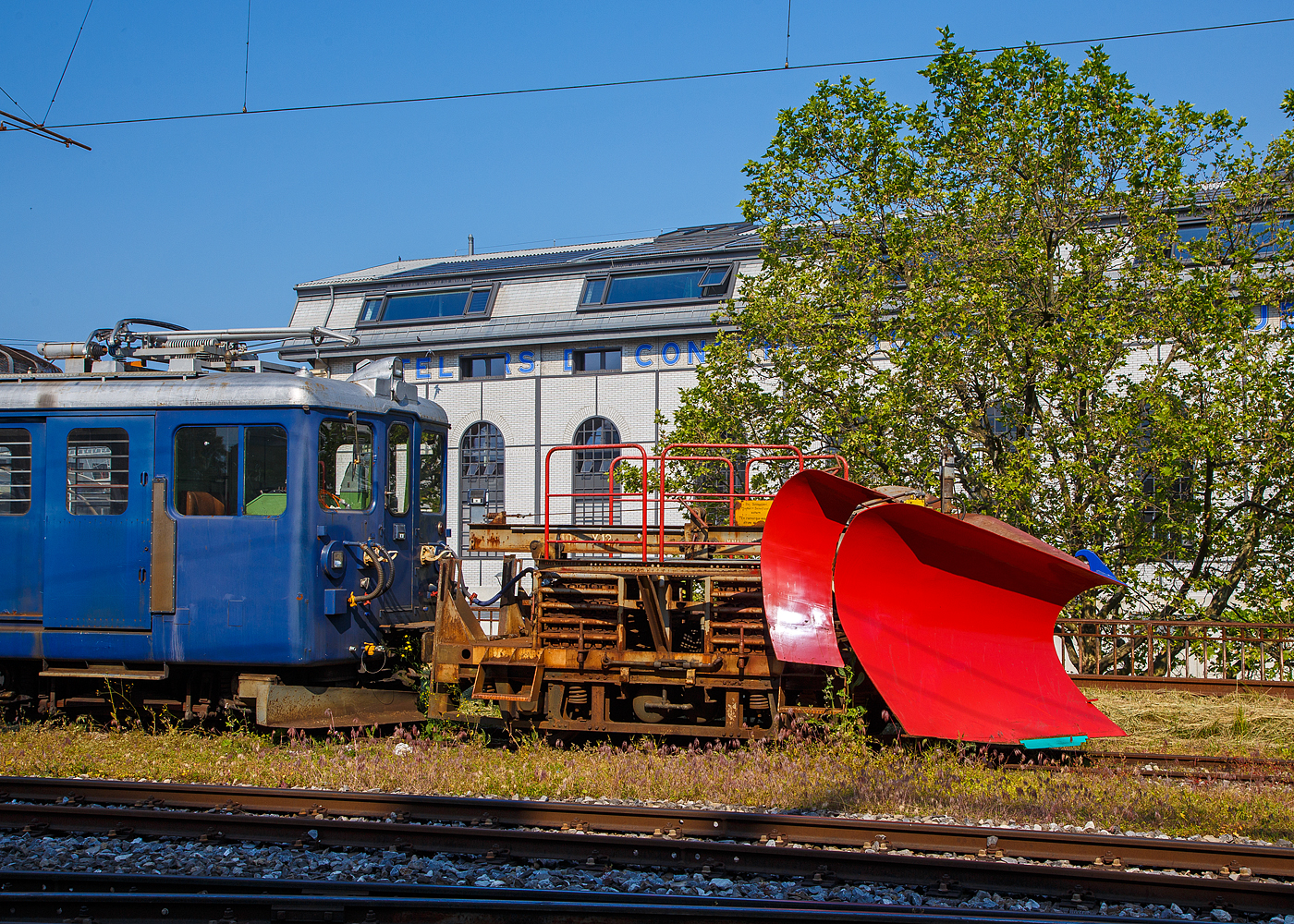 Der MOB Schneepflug X 12 vor dem Triebwagen BDe 4/4 3006 wartet am 28. Mai 2023 in Vevey noch auf Schnee.

Der Schneepflug wurde 1964 in den Werkst�tten der MOB auf ein altes SWS Drehgestell (vom B4 48) aufgebaut. 

Der doppelseitige Pflugkeil l�sst sich hydraulisch heben. Beidseitig ausklappbare Zusatzfl�gel. Der Pflug wird w�hrend der Fahrt nicht bedient, er kann aber gehoben und gesenkt werden. Um auf das hohe Gewicht von 12 t (6t Achsdruck)  zu kommen, sind liegen geschichtet in zwei Boxen etliche Schienenst�cke (Ballast 6,2 t). Im Jahr 2014 beikam der Pflug neue elektrische Anschl�sse, Hydraulikleitung und Hydraulikzylinder.

TECHNISCHE DATEN:
Hersteller/ Erbauer: MOB
Spurweite: 1.000 mm
Anzahl der Achsen: 2 
L�nge �ber Puffer: 4.520 mm (bzw. 5.610 mm �ber Pflugkeil)
Breite: 2.800 mm
Achsabstand: 2.300 mm
Laufraddurchmesser: 750 mm (neu)
Eigengewicht: 12t
V max: 50 km/h
Max Schneer�um H�he / Breite: 1.150 mm / 3.400 mm