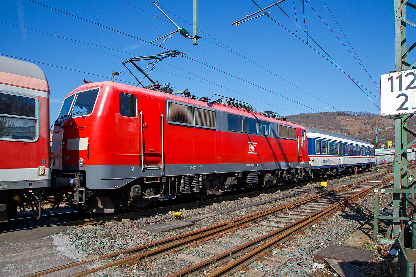 Die 111 200-2 (91 80 6111 200-2 D-GfF) der Gesellschaft für Fahrzeugtechnik mbH, eingereiht in einen National Express Personenzug am 24.03.2021 bei einer Zugdurchfahrt durch Niederschelden, hier passiert er gerade den Bü 343 (Km 112,183 der Siegstrecke KBS 460).

Die Lok wurde1982 von Krupp unter der Fabriknummer 5511gebaut, der elektrische Teil wurde von AEG unter der Fabriknummer 9026 geliefert. Bis 2019 war die Lok bei der DB Regio.
