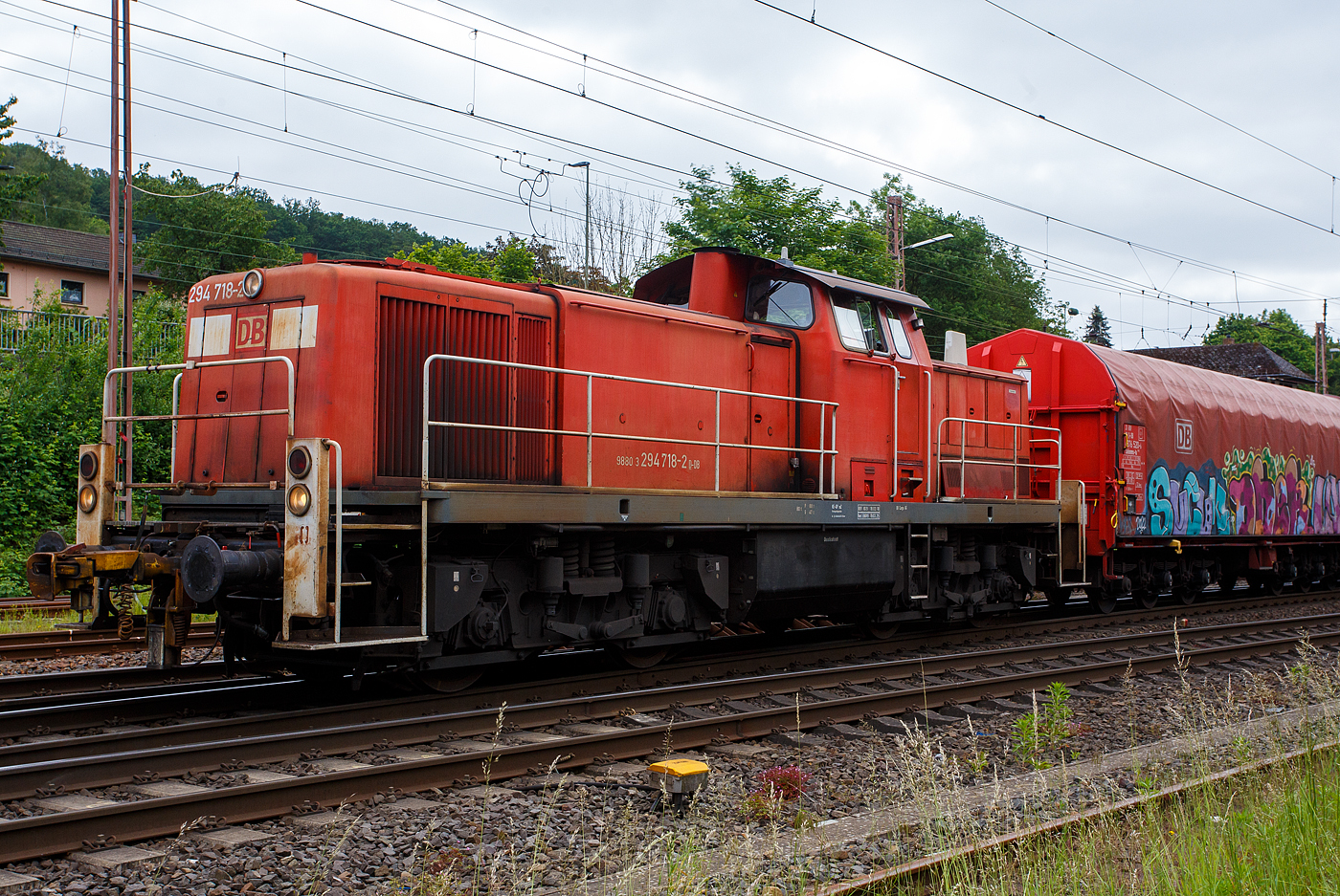 Die 294 718-2 (98 80 3294 718-2 D-DB), eine remotorisierte V 90 der DB Cargo AG drückt am 03 Juni 2024 einen langen Coilzug nun in den Gbf Kreuztal. Der Zug kam vom Werk Kreuztal-Eichen der thyssenkrupp Steel Europe AG (ehem. Eichener Walzwerk).

Die Lok wurde 1971 bei MaK in Kiel unter der Fabriknummer 1000526 gebaut und als 290 218-3 an die DB geliefert. Die Ausrüstung mit Funkfernsteuerung (Typ Krauss-Maffei) und Umzeichnung in 294 218-3 erfolgte 1996. Im Jahr 2002 erfolgte durch die DB Fahrzeuginstandhaltung GmbH, in Cottbus eine Remotorisierung durch einen neuen MTU 90° V-8-Zylinder-Dieselmotor mit Common-Rail-Einspritzsystem, Abgas-Turbolader und Ladeluftkühlung, vom Typ 8V 4000 R41. Der Motor ist auf eine Leistung von 1.000 kW (1.341 PS) bei 1.800 U/min gedrosselt. Auch wurden eine neue Lüfteranlage und ein neuer Luftpresser eingebaut, zudem bekam die Lok ein Umlaufgeländer. Durch die Remotorisierung und den Umbau erfolgte auch die Umzeichnung in die heutige 294 718-2.