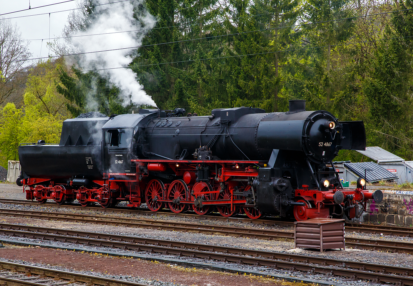 Die 52 4867 / 052 867-3 (90 80 0052 867-3 D-HEF) der Historische Eisenbahn Frankfurt e.V., ex GKB 152.4867 (Graz-Köflacher Eisenbahn- und Bergbaugesellschaft), ex ÖBB 152.4867, ex DRB 52 4867, am 22 April 2017 beim Bahnhof Au/Sieg.

Die Güterzug-Dampflokomotive 52 4867 wurde 1943 bei Maschinenbau und Bahnbedarf AG in Potsdam-Babelsberg unter der Fabriknummer 13931 gebaut und an die Deutschen Reichsbahn geliefert. Nach dem Krieg blieb sie in Österreich und wurde zur ÖBB 152.4867, 1970 kam sie zur GKB und 1980 kaufte die HEF die Lok.

So ist diese Lok noch eine Ur-52er (also keine Roko-Lok) mit Barrenrahmen. Barrenrahmen, wie sonst allgemein bei der Deutschen Reichsbahn üblich, wurden von den Lokomotivfabriken bei den ersten Lieferungen der Baureihe 52 noch eingebaut. Dies aber nur solange wie noch vorgefertigte Rahmen, für die zugunsten der BR 52 eingestellte Produktion, der in den Abmessungen identischen Baureihe 50, lagerte. Später wurden sie mit geschweißtem Blechrahmen gefertigt.

In Österreich befanden sich nach Kriegsende über 700 Lokomotiven, von denen nach Ausmusterungen, Rückgaben, Tauschen und Beschlagnahmen 1953 letztlich noch 313 für die Umzeichnung auf den neuen ÖBB-Nummernplan übrigblieben, die bei den Österreichischen Bundesbahnen unter Beibehaltung der Nummerierung als Reihe 52 eingereiht wurden, aber nach österreichischer Tradition mit einem Punkt zwischen Stamm- und Ordnungsnummer. Die 37 Maschinen der BR 52, die auf einem Barrenrahmen aufgebaut waren, erhielten die Reihenbezeichnung 152 (eine „1“ vor die 52). Die GKB hatte zwischen 1968 und 1973 13 Barrenrahmenlokomotiven der Baureihe 152 gekauft. Zu ihnen zählte auch diese 52 4867, die nach ihrer Ausmusterung wieder nach Deutschland gelangte.