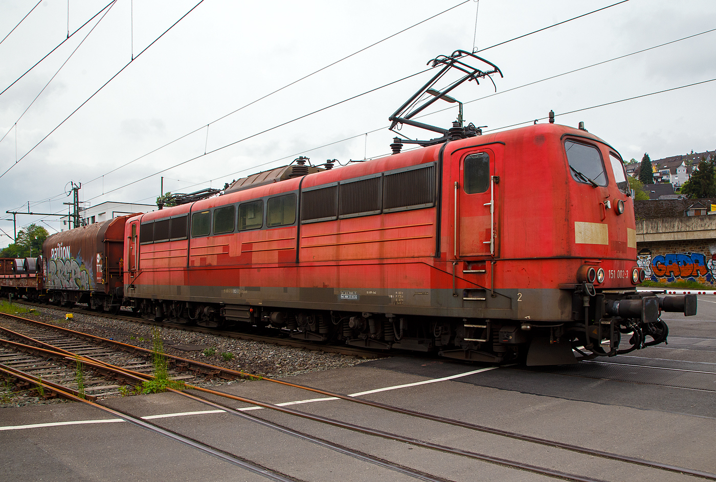 Die an die DB Cargo AG vermietete Railpool 151 002-3 (91 80 6151 002-3 D- Rpool) f�hrt mit einem gemischten G�terzug am 11.05.2023 durch Niederschelden (hier beim B� 343 – km 112,183 der Siegstrecke) in Richtung Siegen.

Die Lok wurde 1973 von Krupp in Essen unter der Fabriknummer 5174, der elektrische Teil ist von AEG unter Fabriknummer 8820, gebaut, und an die Deutsche Bundesbahn geliefert. Bis zum 31.12.2016 geh�rte sie zur DB Cargo AG. Zum 01.01.2017 wurden je 100 sechsachsige elektrische Altbau-Lokomotiven der Baureihen 151 und 155 an ein Konsortium aus dem Lokvermieter Railpool verkauft. Die DB Cargo mietet daraufhin 100 Loks von Railpool wieder an. Die anderen Maschinen werden dem freien Markt angeboten.

Diese sechsachsigen Loks (Co’Co’) sind immer noch starke Zugpferde, und so manche moderne Lok hat nicht diese Leistungsf�higkeit. Mit einer Stundenleistung von 6.288 kW (8.550 PS) bei 92 km/h und einer Anfahrzugkraft von 395 kN k�nnen diese Loks 3.000 t Z�ge bei 3 ‰ Steigung noch mit einer Dauergeschwindigkeit 75 km/h ziehen, bei 2.000 t Z�gen sind es 100 km/h.