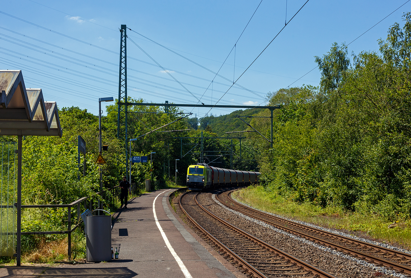 Die an die Dortmunder Eisenbahn GmbH (DE) vermietete SIEMENS Vectron Dual Mode 248 034-1  Phoenix  (90 80 2248 034-1 D-DE) der Captrain Deutschland GmbH fährt am 25 Juni 2024, mit einem Coilzug (Wagen der Gattung Shimmnis-ttu der Ermewa) durch den Bahnhof Scheuerfeld/Sieg in Richtung Siegen. 

Die SIEMENS Vectron DM wurde 2022 von Siemens Mobility GmbH in München-Allach unter der Fabriknummer 23185 gebaut und im Februar 2023 an die Captrain ausgeliefert. Die Lok hat die Zulassung für Deutschland und eine Höchstgeschwindigkeit von 160 km/h. Die Hybridlok (Vectron Dual Mode) kann die Antriebsenergie aus der Fahrleitung beziehen (2.400 kW Leistungen am Rad), oder mittels eines MTU 16V 4000 R84 V16-Zylinder-Dieselmotors (2.400 kW Motorleistung, 2.000 kW Leistungen am Rad) erzeugen. 

Die Dortmunder Eisenbahn GmbH (DE) ist eine private Eisenbahngesellschaft aus Dortmund. Die Dortmunder Eisenbahn GmbH ist ein gemeinsames Tochterunternehmen der Dortmunder Hafen GmbH und der Captrain Deutschland GmbH. Sie ist zu 65 Prozent im Besitz der Captrain Deutschland GmbH (deutsche Tochter der SNCF) und 35 Prozent der Anteile hält die Dortmunder Hafen AG. Die DE Infrastruktur GmbH,  mit ca. 50 Kilometern Gleislänge, gehört zu 81 Prozent der Dortmunder Hafen AG und zu 19 Prozent der Captrain Deutschland GmbH.
