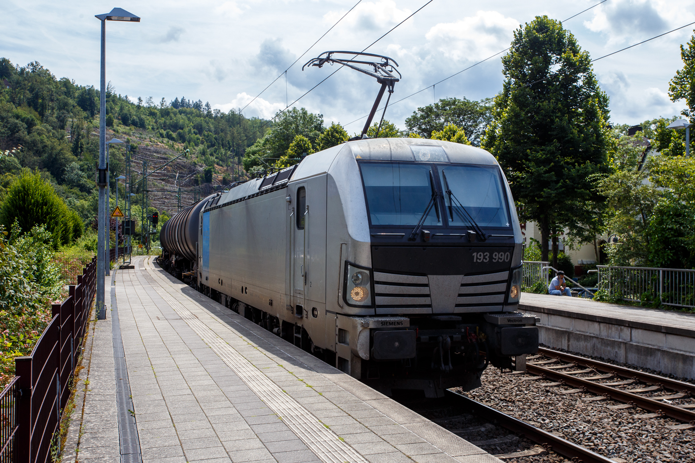 Die an die ecco-rail GmbH vermietete SIEMENS Vectron AC 193 990 (91 80 6193 990-9 D-Rpool) der Railpool GmbH (München) fährt am 18 Juli 2024 mit einem Kesselwagenzug durch den Bahnhof Kirchen (Sieg) in Richtung Siegen. Laut Warntafel 33/1268 (Gefahr-/UN-Nr.) war der Kesselwagenzug beladen mit Erdöldestillate, N.A.G. oder Erdölprodukte, N.A.G.

Die Wechselstromlok (AC 15 kV 16,7 Hz und AC 25 kV 50 Hz) SIEMENS Vectron AC wurde 2019 von Siemens Mobilitiy in München-Allach unter der Fabriknummer 22559 gebaut. Sie ist als Vectron AC B16-2b ausgeführt und hat so die Zulassung für Deutschland, Österreich, Ungarn und Rumänien (D / A / H + RO).