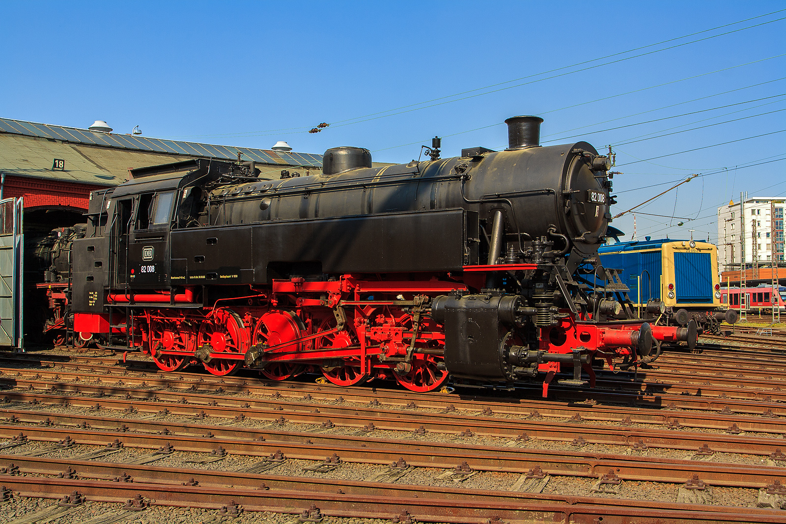 Die DB 82 008 (ex DB 082 008-4) am 23.04.2011 im Südwestfälische Eisenbahnmuseum in Siegen.

Die Lok wurde 1951 bei Krupp in Essen unter der Fabriknummer 2884 gebaut und als 82 008 an die DB geliefert, 1968 wurde sie in DB 082 008-4 umgezeichnet. Die Ausmusterung bei der DB erfolgte am 18.04.1972.

Bis 2014 stand sie (als Leihgabe) im Südwestfälische Eisenbahnmuseum in Siegen, seit April 2014 ist sie nun im DB Museum Koblenz-Lützel zu sehen.

Zum Einheitslok-Typenprogramm der Deutschen Bundesbahn (DB) gehörte auch die fünfachsige Güterzugtenderlokomotive der Baureihe 82. Sie war für den Rangier- und Streckendienst vorgesehen und sollte die fünffach gekuppelten Länderbahnbauarten ablösen, aber auch die durch das komplexe Laufwerk Schad anfällige Einheitslokomotiven der DR-Baureihe 87.

Die Baureihe 82 wurde als erste Neubaulokgattung der DB zwischen 1950 und 1951 von den Unternehmen Krupp und Henschel und in einem weiteren Baulos 1955 von der Maschinenfabrik Esslingen gefertigt.

Bei der Konstruktion versuchte man eine gleichermaßen gut für den Rangier- wie Streckendienst geeignete Maschine zu schaffen. Nach dem bisherigen Stand der Technik widersprachen die für beide Dienste maßgeblichen Konstruktionskonzepte einer gleichwertigen Eignung für beide Dienstbereiche. Dieser Widerspruch sollte durch einen Kessel moderner Bauart und die besondere Laufwerkskonstruktion beseitigt werden.

Um ohne die für eine reine Rangierlokomotive überflüssigen Laufradsätze die für den Streckendienst auch bei höheren Geschwindigkeiten notwendigen sicheren, ruhigen und gleisschonenden Laufeigenschaften zu erhalten, entschied man sich nach Vorversuchen mit einer umgerüsteten preußischen T 16 dazu, das jeweils äußere Kuppelradsatzpaar zu einem Beugniot-Lenkgestell zu vereinigen. Bisherige laufradsatzlose Fünfkuppler-Tenderlokomotiven mit Radsatzanordnung nach Gölsdorf wie etwa die T 16 hatten sich nämlich als für höhere Geschwindigkeiten über rund 40 km/h aufgrund des ausgesprochen unruhigen Laufes als wenig geeignet erwiesen.

Mit den Beugniot-Lenkgestellen waren die Maschinen zugleich ohne die aufwendige Laufwerkstechnik der Baureihe 87 in der Lage enge Gleisbögen (R=100 m), wie z.B. auf der Hamburger Hafenbahn, einwandfrei zu durchfahren.

Bei der Auslegung des Kessels entschied man sich für einen geschweißten Kessel mit großer Strahlungsheizfläche, aber ohne Verbrennungskammer, damit dieser sowohl unter den unregelmäßigen Leistungsanforderungen im Rangierdienst als auch bei Spitzen- und hohen Dauerleistungen im Streckendienst standfest blieb.

Bei der Dimensionierung der Zylinder, die bei einer Rangierlokomotive wegen der aufzubringenden großen Kräfte mit kleinem Durchmesser, bei einer Streckenlokomotive hingegen zur Ausnutzung der Dampfdehnung großvolumig auszulegen gewesen wären, entschied man sich für einen Kompromiss. Dieser führte allerdings, wie vom Bauartdezernenten Friedrich Witte vorhergesagt, zu einem erhöhten Brennstoffverbrauch. Im Rangierdienst schwankte der Mehrverbrauch zur T 16 um 10 bis 19 %, im Streckendienst sogar um 30 %.

Beim Laufwerk wurde nur der dritte Treibradsatz, fest im Rahmen gelagert. Die beiden jeweils außen liegenden Kuppelradsatzpaare verband man mit Beugniot-Hebeln zu jeweils einem Lenkgestell. Die Endradsätze waren um insgesamt 52 mm seitlich verschiebbar, der zweite bzw. vierte Kuppelradsatz noch um insgesamt 36 mm.

Die Lokomotiven der Baureihe 82 bewältigten eine Wagenzugmasse von 800 t in der Ebene mit 70 km/h. Auf Steigungen von 10 Promille konnten noch 400 t mit 40 km/h befördert werden.

Belegt sind Einsätze vor allem auf den Rangierbahnhöfen in Bremen und Hamm sowie den Hafenbahnen von Emden und Hamburg. Im Streckendienst konnten die 82er auf den Steilrampen Siegerland und Westerwald und im Schwarzwald auf der Murgtalbahn beobachtet werden.

Neben einem hohen Schmierölverbrauch bemängelte der Betriebsdienst an der Baureihe 82 vor allem außer den problematischen Heißdampfreglern und schlecht funktionierenden Strahlpumpen einen raschen, durch Verschmutzung bedingten, Verschleiß der Lenkgestelle.

Die Ausmusterung begann bereits 1966, Auslauf-Bw war Koblenz-Mosel, wo die letzte Maschine dieses Typs 1972 abgestellt wurde. Die Baureihe war damit früher aus dem Dienst geschieden als die Baureihe 94, welche sie ja ersetzen sollte.
Fast alle Lokomotiven dieser Baureihe wurden nach Einsatzende verschrottet, lediglich die hier gezeigte 82 008 stellte man 1974 als Denkmal am Bahnhof Lingen (Ems) auf, sie gelangte so in den Bestand des DB Museums. Nach Stationen in Neumünster (2003-2010) und Siegen (2010-2014) befindet sie sich nunmehr im DB Museum Koblenz.

Technische Daten der Baureihe 82:
Gebaute Anzahl: 41 (DB 82 001 - 041)
1435 mm (Normalspur)
Achsformel / Bauart: E h2t
Gattung: Gt 55.18
Länge über Puffer: 14.060 mm
Höhe: 4.450 mm
Gesamtachsstand: 6.600 mm
Leergewicht: 69,7 t
Dienstgewicht: 87 t
Achslast:17,4 t
Höchstgeschwindigkeit: 70 km/h (vorwärts / rückwärts)
Leistung: 1.290 PSi (949 kW)
Treibraddurchmesser: 1.400 mm
Steuerungsart: Heusinger
Zylinderanzahl: 2
Zylinderdurchmesser : 600 mm
Kolbenhub: 660 mm
Kesselüberdruck: 14 bar
Anzahl der Heizrohre: 113
Anzahl der Rauchrohre: 38
Heizrohrlänge: 4.000 mm
Rostfläche: 2,39 m2
Überhitzerfläche: 51,90 m2
Verdampfungsheizfläche: 122,21 m2
Kohlenvorrat: 4 t
Wasservorrat: 11 m3
Seit 1960 ist die 82 008 mit einer Riggenbach-Gegendruckbremse ausgerüstet.

Quellen: wikipedia, eisenbahn-museumsfahrzeuge.de
