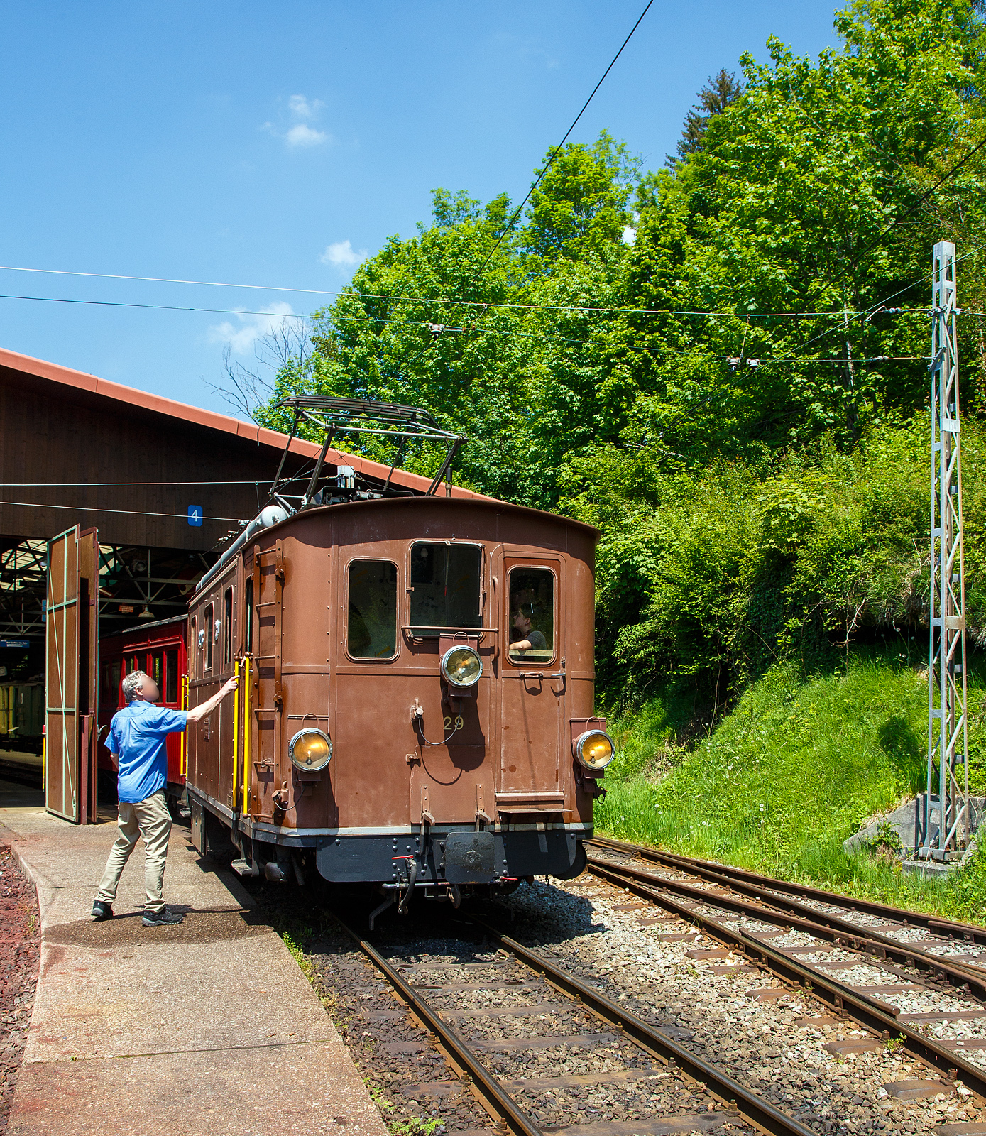 Die ex BOB HGe 3/3 29 der Museumsbahn Blonay–Chamby rangiert  am 27.05.2023 im Museumsareal in Chaulin.

Die elektrischen Lokomotiven für den gemischten Zahnrad- und Adhäsionsbetrieb HGe 3/3 29 wurde 1926 von der SLM - Schweizerische Lokomotiv- und Maschinenfabrik in Winterthur unter der Fabriknummer 3127gebaut, der elektrische Teil wurden von der MFO - Maschinenfabrik Oerlikon geliefert.

Die Berner Oberland-Bahn (BOB) ist eine Schmalspurbahn im Berner Oberland in der Schweiz. Sie führt von Interlaken Ost über Zweilütschinen nach Lauterbrunnen beziehungsweise Grindelwald. Diese Meterspurbahn wurde am 1. Juli 1890 eröffnet  und am 17. März 1914 elektrifiziert. Im Jahr 1914 wurden acht Elektrolokomotiven für den gemischten Zahnrad- und Adhäsionsbetrieb (HGe 3/3 21 bis 28) in Dienst gestellt, um die Dampftraktion zu ersetzen. Die HGe 3/3 Nr. 29 wurde 1928 zur Stärkung des Parks erworben. Sie wurden bis Mitte der 1960er Jahre genutzt, danach wurden einige davon in Reserve gehalten. Die HGe 3/3 29 wurde 2014 an Blonay-Chamby verkauft.

Diese elektrischen Lokomotiven für den gemischten Zahnrad- und Adhäsionsbetrieb der Baureihe HGe 3/3 prägten jahrelang das Erscheinungsbild der Berner Oberland-Bahn. 

Mit den HGe 3/3 wurde das bewährte Konzept der zehn vorhandenen Dampflokomotiven HG 3/3 mit getrenntem Adhäsions- und Zahnradantrieb übernommen. Ein starker Elektromotor wirkte auf die drei mit Stangen gekuppelten Achsen im Adhäsionsantrieb. Ein zweiter baugleicher Motor diente als Antrieb des Treibzahnrads. Das zweite Zahnrad war nicht angetrieben und fungierte als Bremszahnrad. Während im Adhäsionsbetrieb ein Elektromotor verwendet wurde, standen im Zahnradbetrieb beide Motoren in Serie geschaltet im Einsatz. Auch war eine Widerstandsbremse eingebaut.

Typisches äußeres Merkmal der meterspurigen HGe 3/3 21 bis 28 und der nachgelieferten HGe 3/3 29 war ein wuchtiger Pantograf mit zwei weit voneinander angebrachten Schleifstücken.

Nachdem an den Lokomotiven 21 bis 28 verschiedene kleinere Verbesserungen vorgenommen wurden, wurde 1926 eine weitere Lokomotive, diese 29, in einer in weiteren Details verbesserten Ausführung nachbeschafft. Äußerlich ist die nachbeschaffte Lokomotive daran zu erkennen, dass das mittlere Frontfenster gegenüber den beiden seitlichen Frontfenstern sichtbar erhöht ist.

Nach der Inbetriebnahme der elektrischen Personen- und Gepäck-Triebwagen MOB ABDeh 4/4 301 bis 303 im Jahre 1949 wurden die Lokomotiven ins zweite Glied verdrängt. Mit der kontinuierlichen Lieferung weiterer Triebwagen sowie der Bildung von Pendelzügen wurden die Lokomotiven auch wegen der geringen Höchstgeschwindigkeit immer weniger eingesetzt, Stück für Stück ausgemustert und dann abgebrochen. Letztmals waren die beiden noch vorhandenen Lokomotiven HGe 3/3 24 und HGe 3/3 29 im Jahre 2013 fahrplanmäßig vor Sonder- und Dienstzügen im Einsatz.

TECHNISCHE DATEN:
Spurweite: 1.000 mm
Achsfolge: Cz
Zahnstangensystem: Riggenbach
Länge über Puffer: 8.240 mm
Achsabstand: 2 x 1.750 = 3.500 mm
Treibraddurchmesser:  910 mm
Leergewicht: 36,5 t
Leistung: 2 x 150 kW = 300 kW (420 PS), bei Adhäsion 150 kW
Übersetzung: Adhäsion 1:4.27 / Zahnrad 1:6.00
Höchstgeschwindigkeit: 40 km/h (Adhäsion) / 15 km/h (Zahnrad)
Anhängelast: 125 t auf 25 ‰; 85 t auf 90 ‰ nach Lauterbrunnen; 60 t auf 120 ‰ nach Grindelwald
Stromsystem: 1:500 V DC (Gleichstrom)
