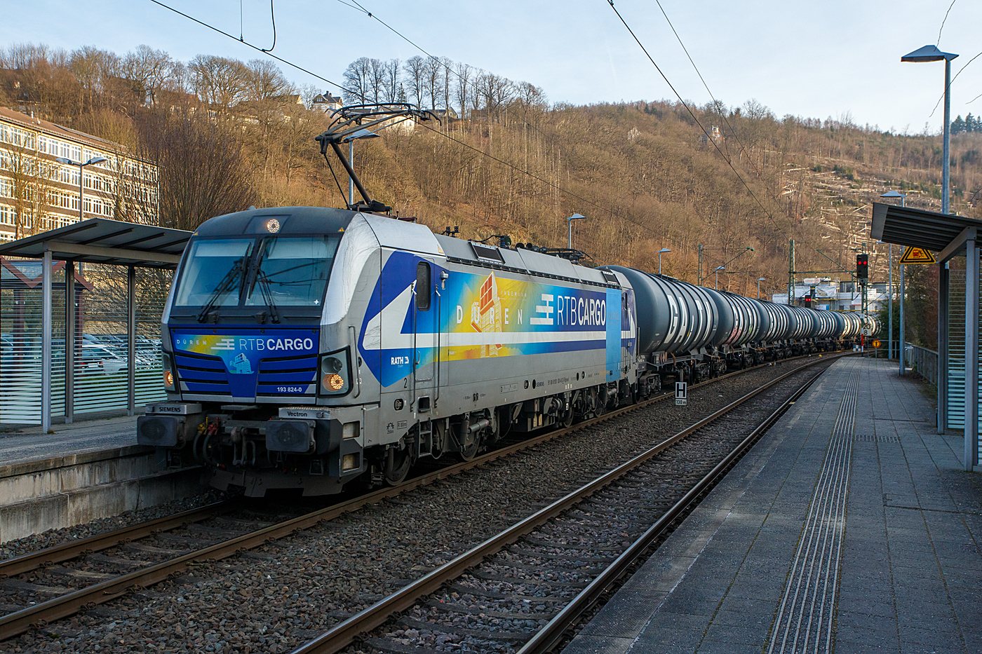 Die für die Rurtalbahn Cargo GmbH fahrende Vectron 193 824-0  Düren  (91 80 6193 824-0 D-Rpool) der Railpool fährt am 22 Januar 2026 mit einem Kesselwagenzug durch Kirchen/Sieg in Richtung Siegen. Laut Gefahrgut- Warntafeln 30/1202 waren die Wagen mit Dieselkraftstoff oder leichtem Heizöl beladen.

Die SIEMENS Vectron AC (200 km/h - 6.4 MW) wurde 2016 von SIEMENS Mobilitiy in München-Allach unter der Fabriknummer 22054 gebaut. Sie hat die Zulassung für D, A, H und RO.