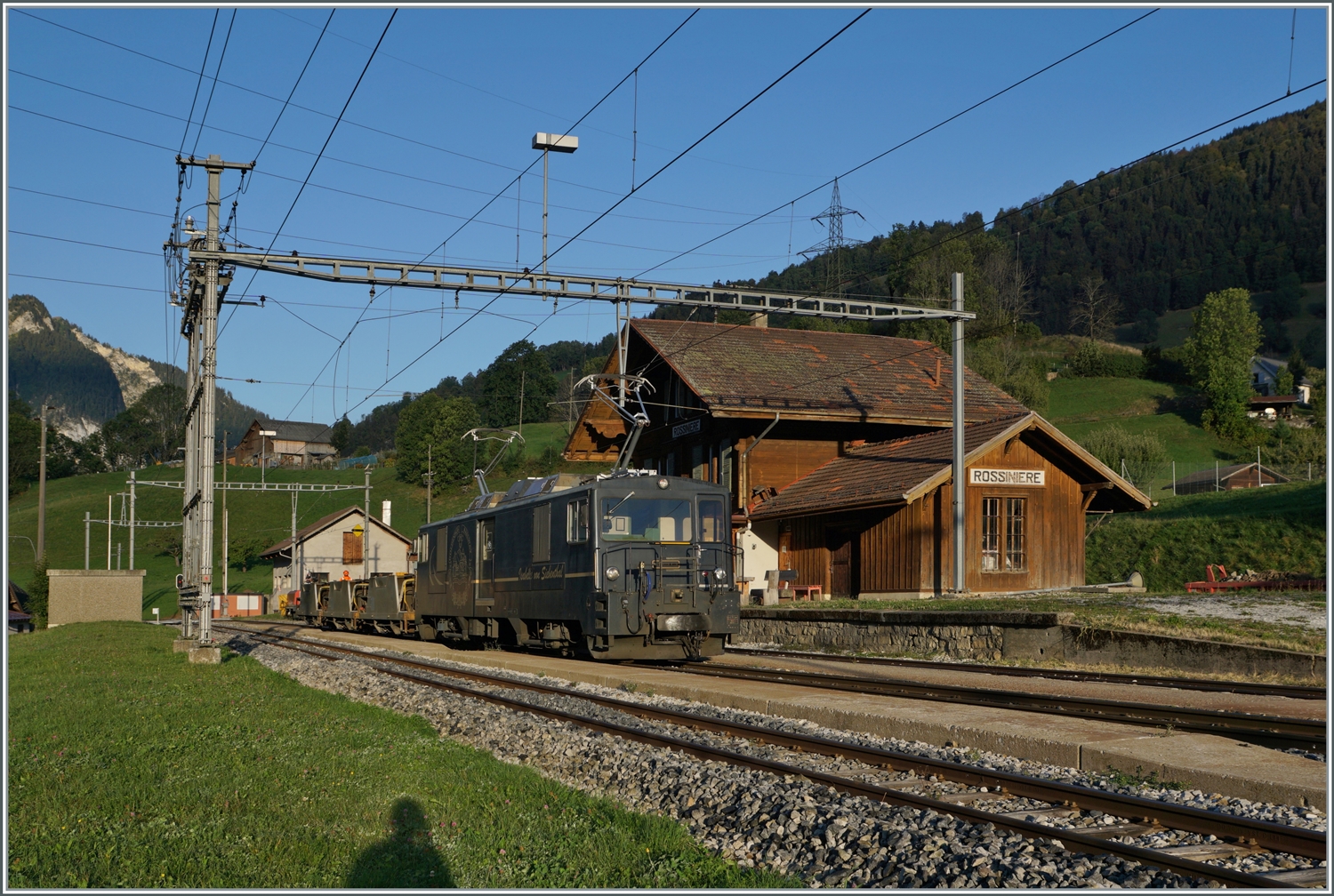 Die GDe 4/4 6002 steht in Rossinière mit einem kurzen Güterzug. Die Lok schob die Wagen und wartet nun auf den Gegenzug. 

29. September 2023
