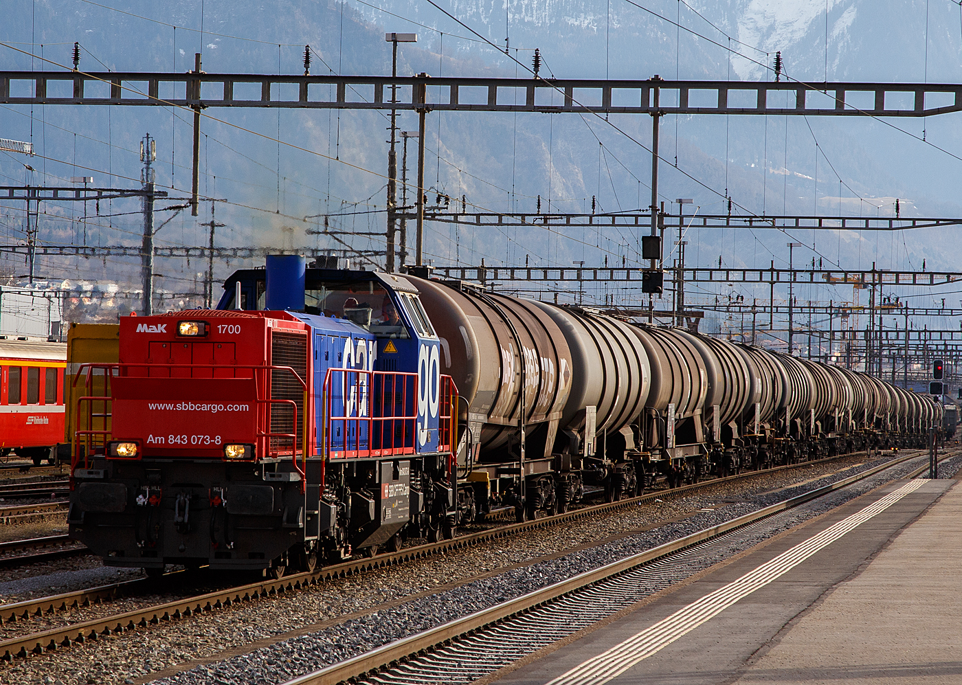 Die SBB Cargo Am 843 073-8 (eine modifizierte Vossloh MaK 1700) fährt am 20.02.2017 mit einem langen Kesselwagenzug (Wagen der Gattung Zans, laut Warntafel 30/1202 für/mit Heizöl / Dieselkraftstoff) in den Bahnhof , wo der Zug später von einer Re 4/4 II übernommen wird.

Die Lok wurde 2004 von Vossloh in Kiel unter der Fabriknummer 1001421 gebaut und an die SBB Cargo AG in Basel geliefert. 