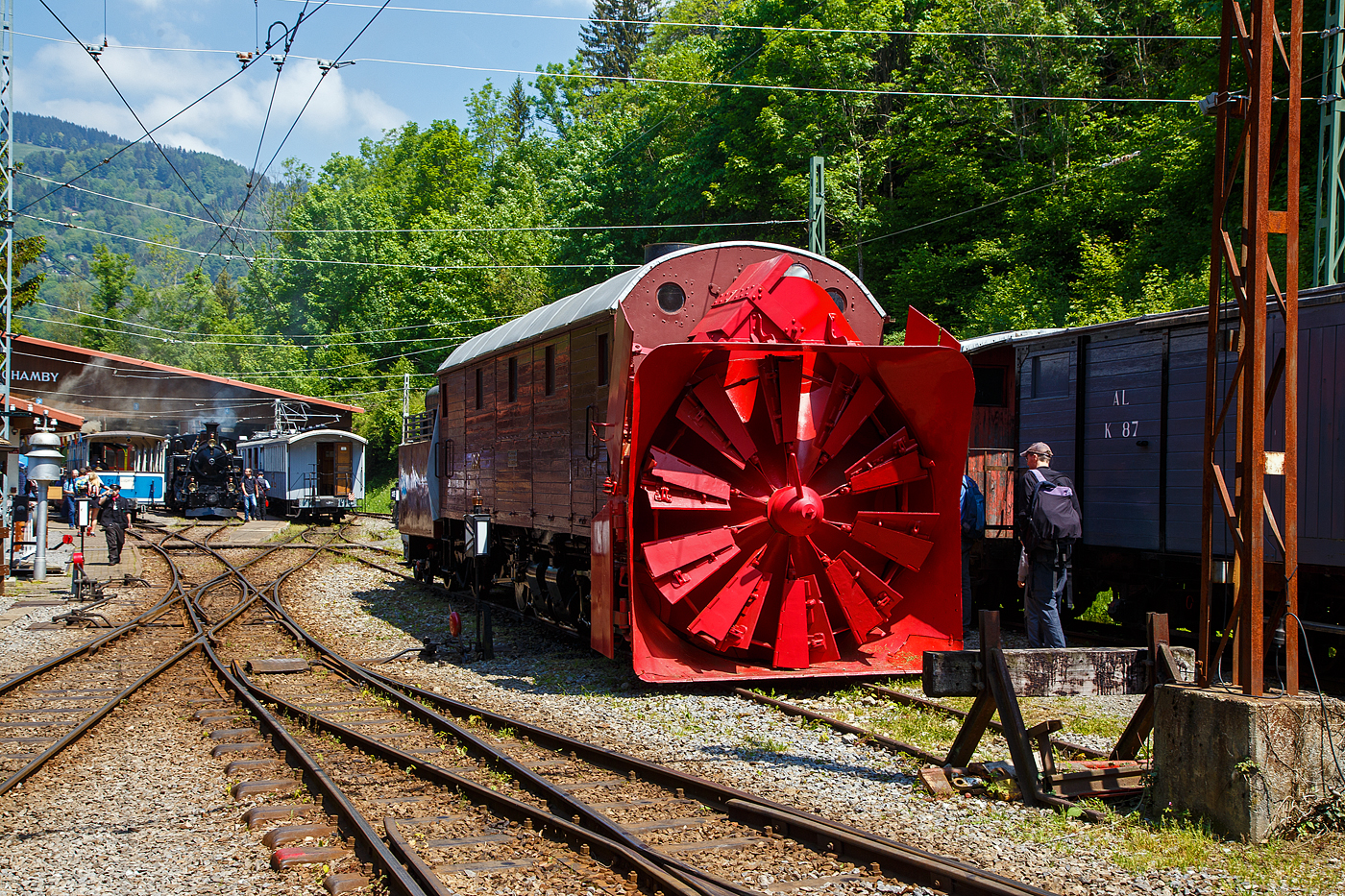 Die Selbstfahrende Dampfschneeschleuder R 1052 (ex Berninabahn) BB R 1052, ex RhB R 14, ex RhB Xrot d 9214), der Museumsbahn Blonay-Chamby, hier am 27.05.2023 auf dem Museums-Areal der (BC) in Chaulin.

Die Schneeschleuder wurde 1912 von der Schweizerischen Lokomotiv- und Maschinenfabrik (SLM) unter der Fabriknummer 2299 als R 1052 für die Berninabahn gebaut, 1944 um bezeichnet in RhB R 14, 1954 um nummeriert in RhB Xrot d 9214 (Die Bezeichnung Xrot d setzt sich zusammen aus: X = Dienstfahrzeug, rot = rotierend, d = dampfgetrieben.), 1990 ging sie an die DFB, 1996 wurde sie im Tausch gegen die ehemalige RhB R 12 von der B-C übernommen.

Dieses Fahrzeug wie auch das heute noch bei der RhB betriebsfähige Schwesterfahrzeug Xrot d 9213 (ex BB R 1051) sind dampfgetriebene Schneeschleudern mit eigenem Antrieb die für die Berninabahn (BB) gebaut wurden, die seit 1944 zur Rhätischen Bahn gehört. Im Gegensatz zu den bisher gebauten Fahrzeugen, auch der zwei Dampfschleudern der RhB-Stammstrecke, handelt es sich bei den beiden Bernina-Schleudern um selbstfahrende Fahrzeuge. Die Berninabahn entschied sich hierzu, weil in den engen Kurven mit nicht genügend hoher Kraft geschoben werden konnte und die Bahn selbst keine Fahrdraht-unabhängigen Triebfahrzeuge besaß. Die Schleudern wurden dennoch normalerweise mit Schiebetriebfahrzeugen eingesetzt, damit die gesamte Kesselleistung für die Dampfmaschine des Schleuderrades zur Verfügung stand.

Mit der Übernahme der Berninabahn durch die Rhätische Bahn (RhB) erhielten die beiden Schleudern die neuen Bezeichnungen R 13 und R 14, 1950 dann Xrot d 9213 und 9214. Die beiden Fahrzeuge befanden sich bis 1967 im regelmäßigen Einsatz und wurden danach durch modernere Schleudern ersetzt. Die Xrot d 9213 wird von der RhB im Heimatdepot in Pontresina weiterhin betriebsfähig gehalten. Sie wird heute vor allem zu touristischen Zwecken noch betrieben, und zwar im Rahmen so genannter Fotofahrten; zuweilen kommt sie aber auch noch bei der Räumung zum Einsatz.

Die Achsformel ist C'C', das Fahrzeug verfügen nach Bauart Meyer über zwei dreiachsige Triebdrehgestelle die durch vier Zylinder angetrieben werden, diese befinden sich unten mittig zwischen den Triebgestellen, darüber befindet sich der Antrieb für die Schneeschleuder, die von zwei weiteren Zylindern angetrieben wird. Der Durchmesser des Schleuderrads beträgt 2,5m, welches mit bis zu 170 U/min dreht und so bis zu drei Meter hohe Schneemassen beseitigen kann.
Gekuppelt ist die Schneeschleuder mit einem zweiachsigen Tender.

Die Xrot d 9214 wurde am 26. Januar 1968 zu einem einmaligen Großeinsatz auf der Arosabahn herangezogen. Geschoben von zwei ABDe 4/4 hatte sie die tiefverschneite Strecke zwischen Langwies und Arosa zu räumen und benötigte für den nur acht Kilometer langen Abschnitt acht Stunden.

TECHNISCHE DATEN:
Gebaute Anzahl: 2 (BB 1051, BB 1052)
Hersteller: SLM
Baujahre: 1910 und 1912
Ausmusterung: 1967 (1052/ 9214), Die 1051 ist als RhB Xrot d 9213 betriebsfähig
Spurweite: 1.000 mm (Meterspur)
Achsformel: C'C'
Länge: 13.865 mm
Höhe: 3.800 mm
Breite: 2.800 mm, max. 3.600 mm
Gesamtradstand: 10.655 mm (inkl. Tender)
Kleinster befahrbarer Gleisbogen: R=45 m
Dienstgewicht: 45 t
Dienstgewicht mit Tender: 63,5 t
Höchstgeschwindigkeit: 35 km/h
Indizierte Leistung Antrieb: 221 kW
Indizierte Leistung Schneeschleuder: 368 kW
Treibraddurchmesser: 750 mm
Zylinderanzahl: 4 für Antrieb und 2 für Schneeschleuder
Kesselüberdruck: 14 bar
Wasservorrat: 7 m³
Kohlevorrat: 4 t
