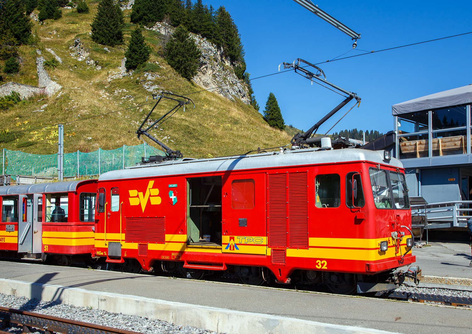Die tpc BVB HGe 4/4 32 „Villars“ hat am 10 September 2023 mit einem Personenzug/Pendelzug (Personenwagen tpc BVB B 51 und Steuerwagen tpc BVB Bt 54) den Bergbahnhof Col-de-Bretaye (1.808 m �. M.) erreicht.

Die BVB HGe 4/4 31 (Baujahr 1953) und hier die 32 (Baujahr 1964) sind schmalspurige gemischte Zahnrad- und Adh�sionslokomotiven mit Gep�ckabteil der ehemaligen BVB - Bex–Villars–Bretaye-Bahn (Chemin de fer Bex–Villars–Bretaye), heute Betriebsteil der tpc - Transports Publics du Chablais. Die Loks wurden von SIG (Schweizerische Industrie-Gesellschaft) in Neuhausen am Rheinfall gebaut, die Elektrik ist von der MFO - Maschinenfabrik Oerlikon. 

Nach der Ablieferung der HGe 4/4 32 „Villars“ wurde 1964 die �ltere HGe 4/4 31 „Lavey“ von SIG und MFO, auf den neuen Stand der Technik wie der der HGe 4/4 32 umgebaut bzw. angepasst.

Heute sind die Loks nicht mehr im Planeinsatz, fr�her bespannten sie vor allem schwere Personenz�ge im Pendelzugbetrieb. Hier an dem Wochenende (08 bis 10 September 2023) feiert die TPC 125 Jahre BVB! (Les TPC c�l�brent les 125 ans du BVB!). So kamen auch historische Z�ge und Triebwagen zum Einsatz. Unteranderem gab es auch an dem Wochenende jeweils Tageskarten f�r das gesamte TPC-Netz f�r g�nstige 10,00 CHF/Tag und Person.

TECHNISCHE DATEN:
Inbetriebsetzung: 1953 (Nr. 31 – 1964 umgebaut)  / 1964 (Nr. 32)
Spurweite: 1.000 mm
Achsfolge: Bo'zz Bo'zz
Zahnstangensystem: Abt
L�nge �ber Puffer: 10.000 mm
Eigengewicht: 24,4 t
Max. Ladegewicht: 0,5 t
H�chstgeschwindigkeit (Adh�sion): 35 km/h
H�chstgeschwindigkeit (Zahnrad): 19 km/h Berg auf / 15 km/h (Talfahrt)
Leistung: 368 kW
Fahrleitungsspannung: 700 V = 

Hier die Strecke der BVB f�hrt hinauf zum Col-de-Bretaye auf 1.808 m �. M. und ist so der h�chste Bahnhof der tpc, mit einer maximalen Neigung von 200 ‰ ist die BVB aber nicht die steilste Strecke, das ist die AL- Aigle-Leysin-Bahn mit 230 ‰ Steigung.
