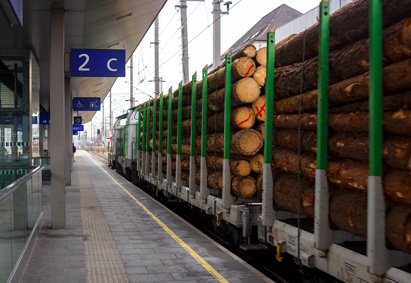 Direkt hinter den beiden V 100 (ex DB BR 211), V100.54 und V100.53 der SETG - Salzburger Eisenbahn Transportlogistik GmbH (auch S-Rail GmbH oder S-Fleet GmbH) am 14 Januar 2025 bei der Zugdurchfahrt im Bahnhof Attnang-Puchheim, ein mit Fichtenrundholz beladener vierachsiger Drehgestell-Flachwagen mit Rungen (Rungenwagen) D-SRA 4723 xxx-x der Gattung Snps „SFlexwood“ der SETG.

Die Salzburger EisenbahnTransportLogistik GmbH (SETG) investierte als erste Privatbahn Europa‘s in Neubau-Rungenwaggons. Das österreichische Eisenbahnunternehmen SETG hat gemeinsam mit dem slowakischen Hersteller Tatravagónka a.s. (in Poprad) einen neuen Holztransportwaggon namens Snps „SFlexwood“ entwickelt. Gegenüber herkömmlichen Rungenwagen verfügt die Neukonstruktion mit 8,8 m² über einen deutlich größeren Ladequerschnitt. Die Waggons sind mit Rungen ausgestattet, die sowohl Rundholz- als auch Schnittholztransport ermöglichen. Teile des Rungenschemels sind dazu im Wagenboden integriert, damit beim Schnittholztransport die gesamten Breite zur Verfügung steht. Die Sortimentslängen können 2,5 bis 17 m betragen und die Nutzlast liegt bei 68 t. Durch den Verzicht auf Stirnwände sollen sich bis zu 25% Fahrenergie einsparen lassen. Insgesamt hat die SETG 180 Einheiten des SFlexwood erhalten, remisiert bzw. einstellt sind sie in Deutschland als D-SRA 4723 xxx-x, die internationale Verwendungsfähigkeit ist TEN-CW. 

SFLEXWOOD ist der neue Standard-Holzwaggon: für unterschiedliche Holzlängen, Rund- und Schnittholz, kundenspezifische Zugslängen und maximal ökologisch.

Kenndaten:
Bei 17,20 m Ladelänge und Bauprofil ‚G2‘ waren letztendlich 8,8 m² Ladequerschnitt das Ergebnis detaillierter Planung. Dies stellt den größten Ladequerschnitt aller Rundholzwaggons in Europa dar. Über 68 Tonnen Nutzlast pro Waggon ergeben ein Ladungsgewicht pro Zug von max. 2.380 Tonnen. Je nach Holzbeschaffenheit lassen sich auf einem SFLEXWOOD-Zug somit bis zu 2.500 Festmeter (fm) verladen. Oder bis zu 4.200 Kubikmeter (m³) Schnittholz pro Zug. Soviel wie noch nie auf Zügen in Zentral- und Osteuropa auf Ganzzügen für den Holztransport Platz gefunden hat. Der SFLEXWOOD ist universell in den meisten Ländern Europas einsetzbar – eine wichtige Voraussetzung im flexiblen Holz-Transportmarkt. Die kompakte Länge des SFLEXWOOD-Waggons ermöglicht flexible, kundenspezifische Zuglängen, weniger Rangierbewegungen bei Be- und Entladung und damit eine optimale Auslastung der oft kurzen Lade-/Entladegleise.

Die Wagenkonstruktion ist für eine Achslast von 25 t aus der Sicht der Festigkeit ausgelegt. Der Wagen ist mit einem 70 mm dicken Holzboden und einer Ladekante ausgestattet, die den Wagenfußboden vor Beschädigungen schützt. Der Fußboden erfordert nur geringen Aufwand. Alle Bedienelemente befinden sich unter dem seitlichen Längsträger und sind so vor ungewollten Beschädigungen während der Handhabung mit dem Ladegut geschützt.

Bahngeschichte geschrieben:
Zum ersten Mal seit dem zweiten Weltkrieg hat in Europa eine Privatbahn in den Neubau von Waggons für den Holztransport investiert. Die SETG stärkt damit in ihrem Kernsegment, dem Transport von Forstprodukten, ihre Kompetenz und bietet ihren Kunden ab sofort den maximal größten und maximal flexibelsten Holz-Ganzzug an: SFLEXWOOD.

TECHNISCHE DATEN der SFLEXWOOD-Wagen:
Hersteller: Tatravagónka a.s., in Poprad (Slowakei)
Baujahr: ab 2023
Spurweite: 1.435 mm (Normalspur)
Länge über Puffer: 18.440 mm
Drehzapfenabstand: 12.900 mm
Achsabstand im Drehgestell: 1.800 mm
Laufraddurchmesser: 920 mm (neu) 
Drehgestelltyp: Y25 Ls-K
Ladefläche: 46,8 m²
Ladelänge: 17.200 mm
Höhe der Ladeebene über SOK: 1.260 mm
Anzahl der Rungenpaare: 10
Rungenhöhe: 2.410 mm
Eigengewicht: ca. 22,0 t
Max. Zuladung bei Lastgrenze S: ca. 68,0 t (ab Streckenklasse D)
Max. Geschwindigkeit: 100 km/h (beladen) / 120 km/h (leer)
Max. Radsatzlast: 22,5 t
Intern. Verwendungsfähigkeit: TEN / CW