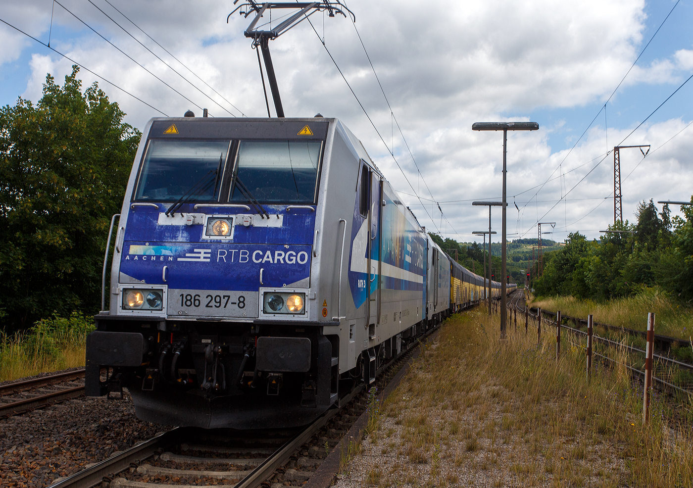 Keine ANGST, ich sehe im gesicherten Bereich vom Bahnsteigzugang (siehe nachfolgendes Bild). Die an die RTB Cargo (RATH Gruppe/Rurtalbahn) vermietete Railpool 186 297-8 (91 80 6186 297-8 D-Rpool), fährt am 11 Juli 2025 mit einer weiteren kalten 185 oder 186er und mit einem langen geschlossen Doppelstock- Autotransportzug der ARS Altmann AG (mit Wagen der Gattung Hccrrs), durch Rudersdorf (Kreis Siegen) in Richtung Siegen bzw. Köln.

Die Bombardier TRAXX F140 MS wurde 2016 von Bombardier in Kassel unter der Fabriknummer 35346 gebaut. Sie hat die Zulassungen/Länderpaketen für Deutschland, Österreich Belgien und die Niederlande (D/A/B/NL).
