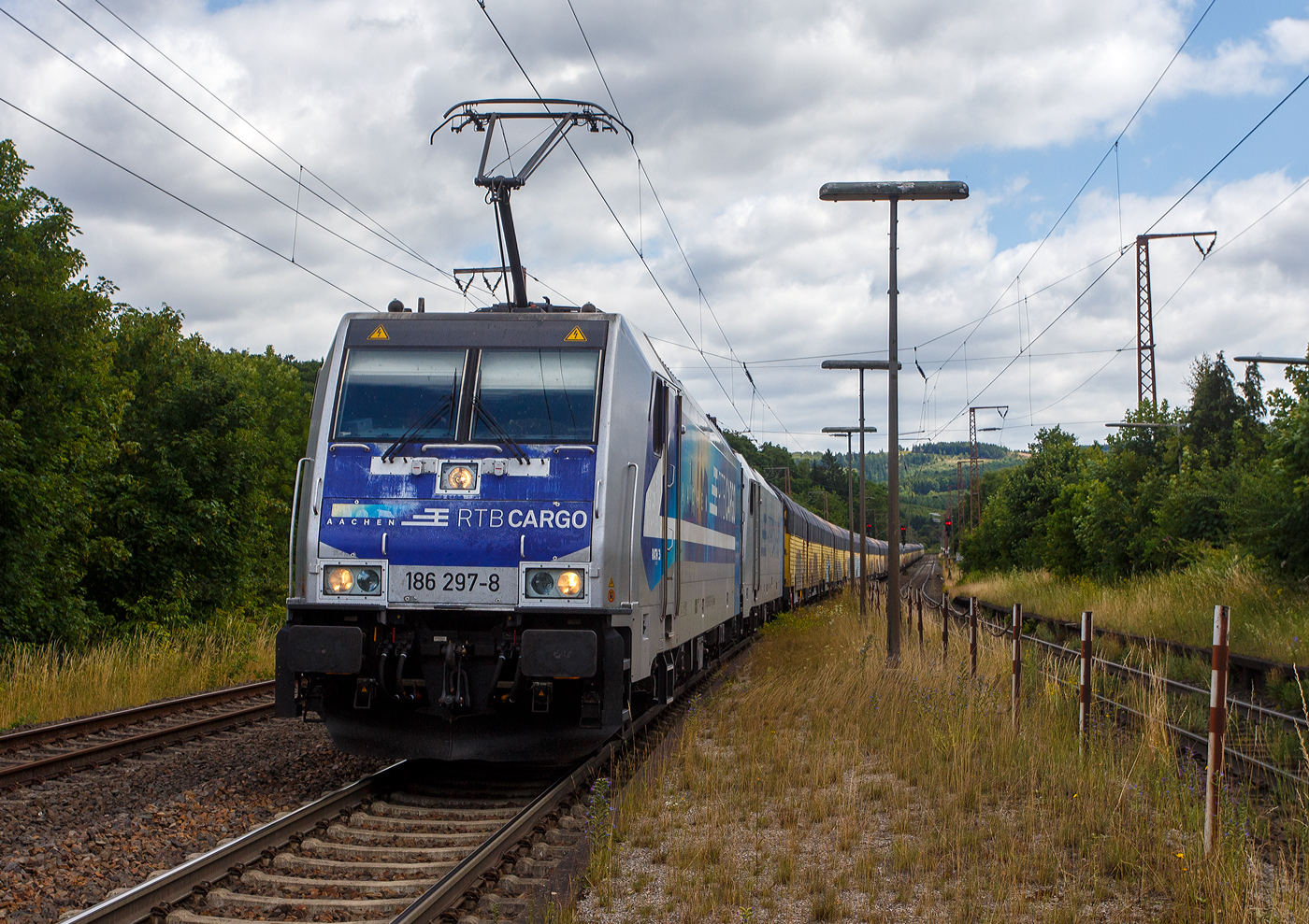 Keine ANGST, ich sehe im gesicherten Bereich vom Bahnsteigzugang (siehe nachfolgendes Bild). Die an die RTB Cargo (RATH Gruppe/Rurtalbahn) vermietete Railpool 186 297-8 (91 80 6186 297-8 D-Rpool), fährt am 11 Juli 2025 mit einer weiteren kalten 185 oder 186er und mit einem langen geschlossen Doppelstock- Autotransportzug der ARS Altmann AG (mit Wagen der Gattung Hccrrs), durch Rudersdorf (Kreis Siegen) in Richtung Siegen bzw. Köln.

Die Bombardier TRAXX F140 MS wurde 2016 von Bombardier in Kassel unter der Fabriknummer 35346 gebaut. Sie hat die Zulassungen/Länderpaketen für Deutschland, Österreich Belgien und die Niederlande (D/A/B/NL).
