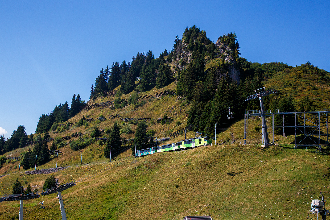 TPC 125 Jahre BVB! (Les TPC célèbrent les 125 ans du BVB!):
Der tpc BVB BDeh 4/4 – 81 „Gryon“ ein elektrischer Personentriebwagen mit Gepäckabteil für den gemischtem Adhäsions- und Zahnradbetrieb der Bex–Villars–Bretaye-Bahn, fährt am 10 September 2023 vom Bergbahnhof Col-de-Bretaye (1.808 m ü. M.) nun wieder hinab nach Villars-sur-Ollon. Vor dem Triebwagen sind die beiden Steuerwagen tpc BVB Bt 61(ex BVB B 53) und der Steuerwagen tpc BVB Bt 63.